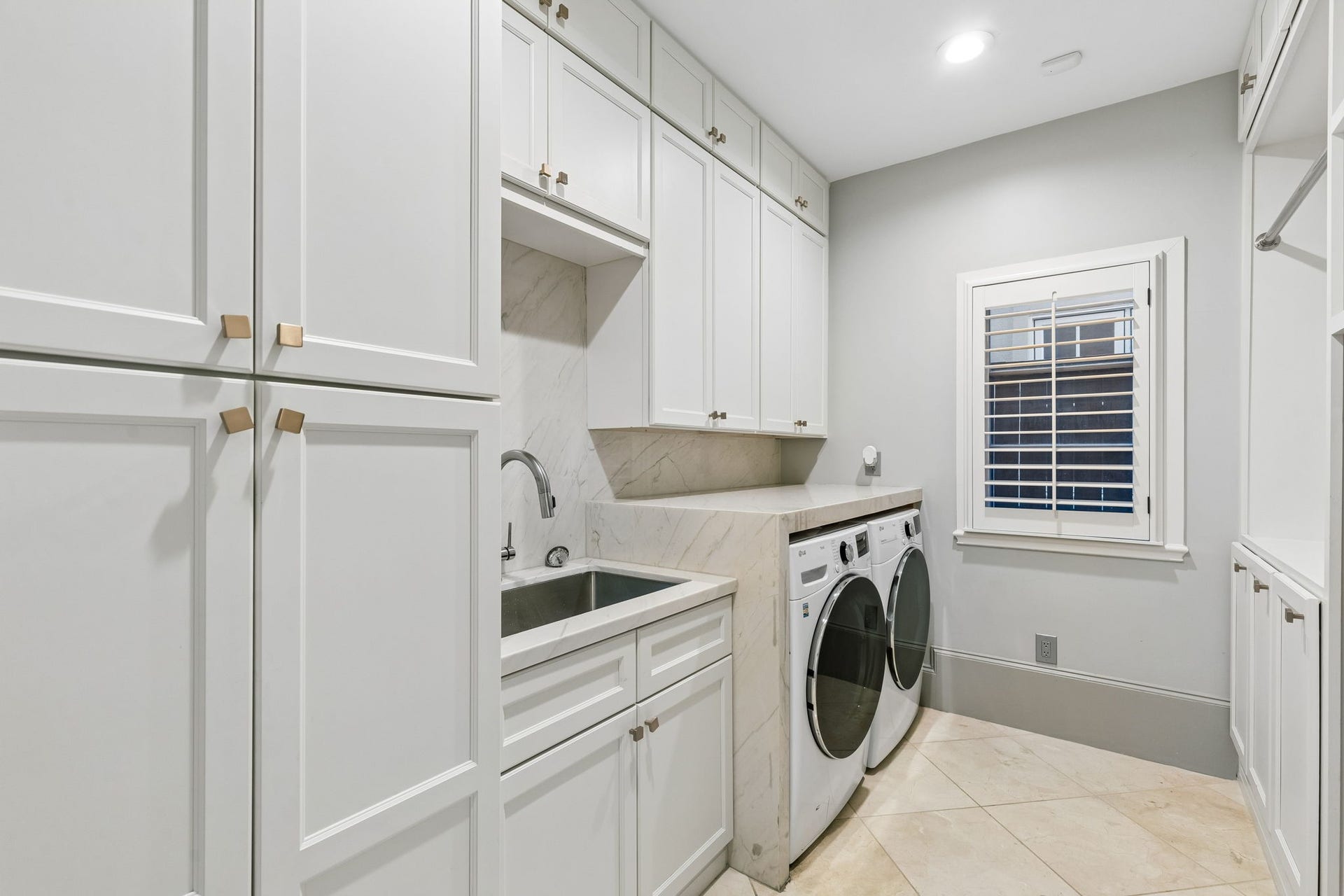 The laundry room measures approximately 10'11" x 7'7" and is designed with Quartzite countertops, wall of shaker-style cabinetry, hanging rack and a utility sink. A climate-controlled 9' x 8' storage closet offers exceptional additional space for seasonal items and household storage.