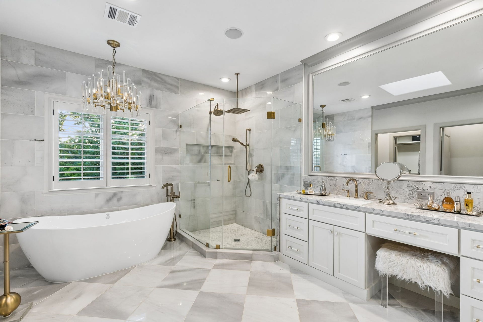 Dual vanities with Quartzite countertops, shaker style cabinetry, and illuminated designer mirrors create a spa-inspired experience.
