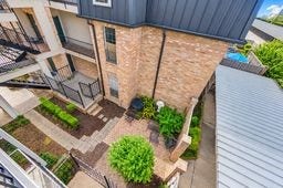 Charming multi-level courtyard with lush greenery and a cozy brick patio, perfect for relaxation and outdoor gatherings.