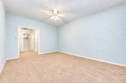 Spacious room with soothing blue walls, plush carpeting, and a ceiling fan, offering a comfortable and inviting atmosphere.