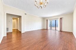 Spacious living area with elegant hardwood floors, ample natural light from large sliding doors, and a charming chandelier.