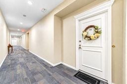 Inviting hallway with elegant dcor, leading to a beautifully adorned door, offering a warm welcome home.