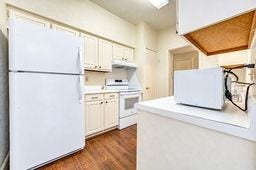 Bright kitchen with classic white cabinetry, modern appliances, and warm wood flooring.