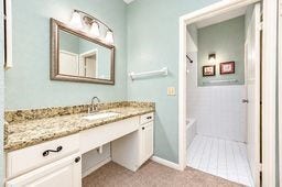 Bright bathroom featuring a granite countertop with a spacious vanity, framed mirror, and a separate shower area with elegant tile flooring.