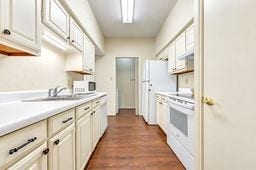 Bright and functional galley kitchen with ample cabinetry, modern appliances, and warm wood flooring, offering a perfect space for culinary creations.
