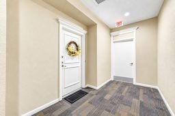 Inviting hallway with neutral tones features a charming door adorned with a decorative wreath, creating a warm and welcoming entryway.