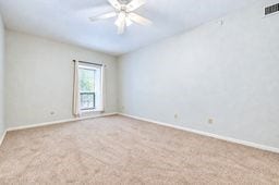 Spacious bedroom with plush carpeting, neutral walls, and abundant natural light from a large window, complemented by a ceiling fan overhead.