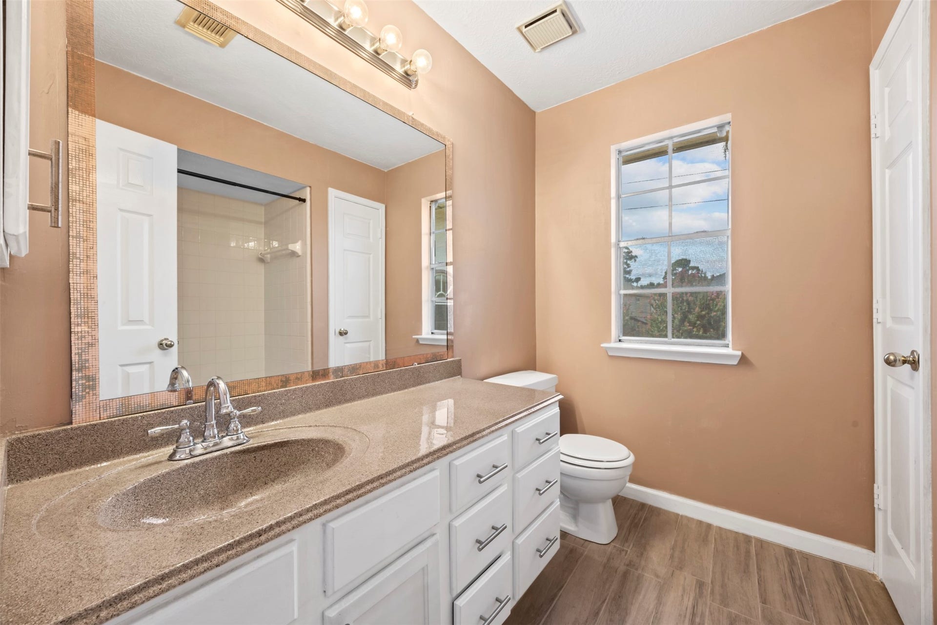 19119 Timber Trace Drive, Humble, TX 77346 Charming bathroom featuring a spacious vanity with ample storage, warm peach walls, and natural light streaming through a large window.