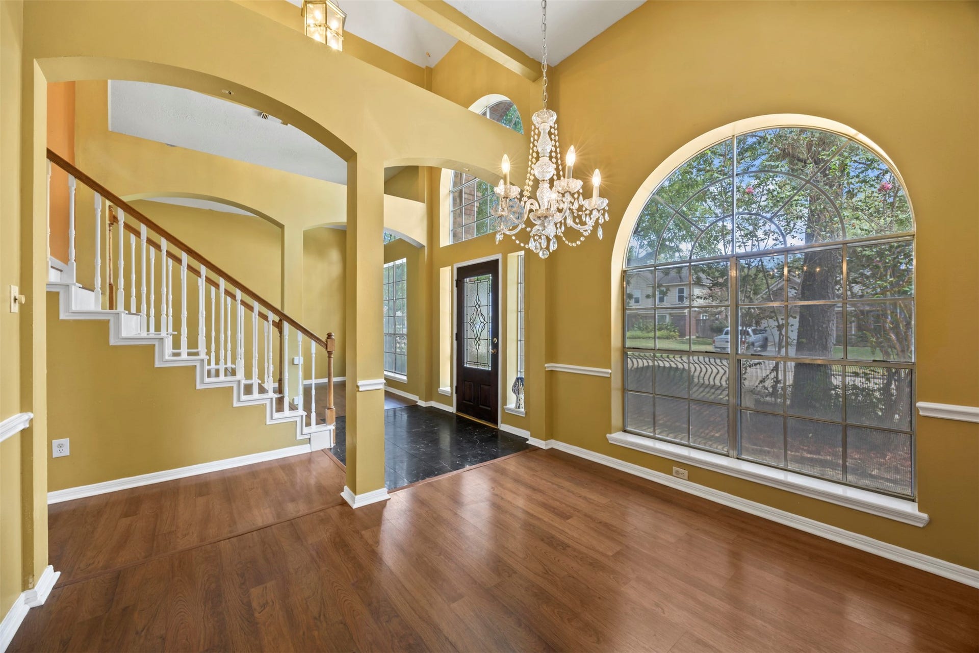 19119 Timber Trace Drive, Humble, TX 77346 Elegant entryway featuring soaring ceilings, a grand staircase, and a stunning chandelier, complemented by large arched windows that flood the space with natural light.