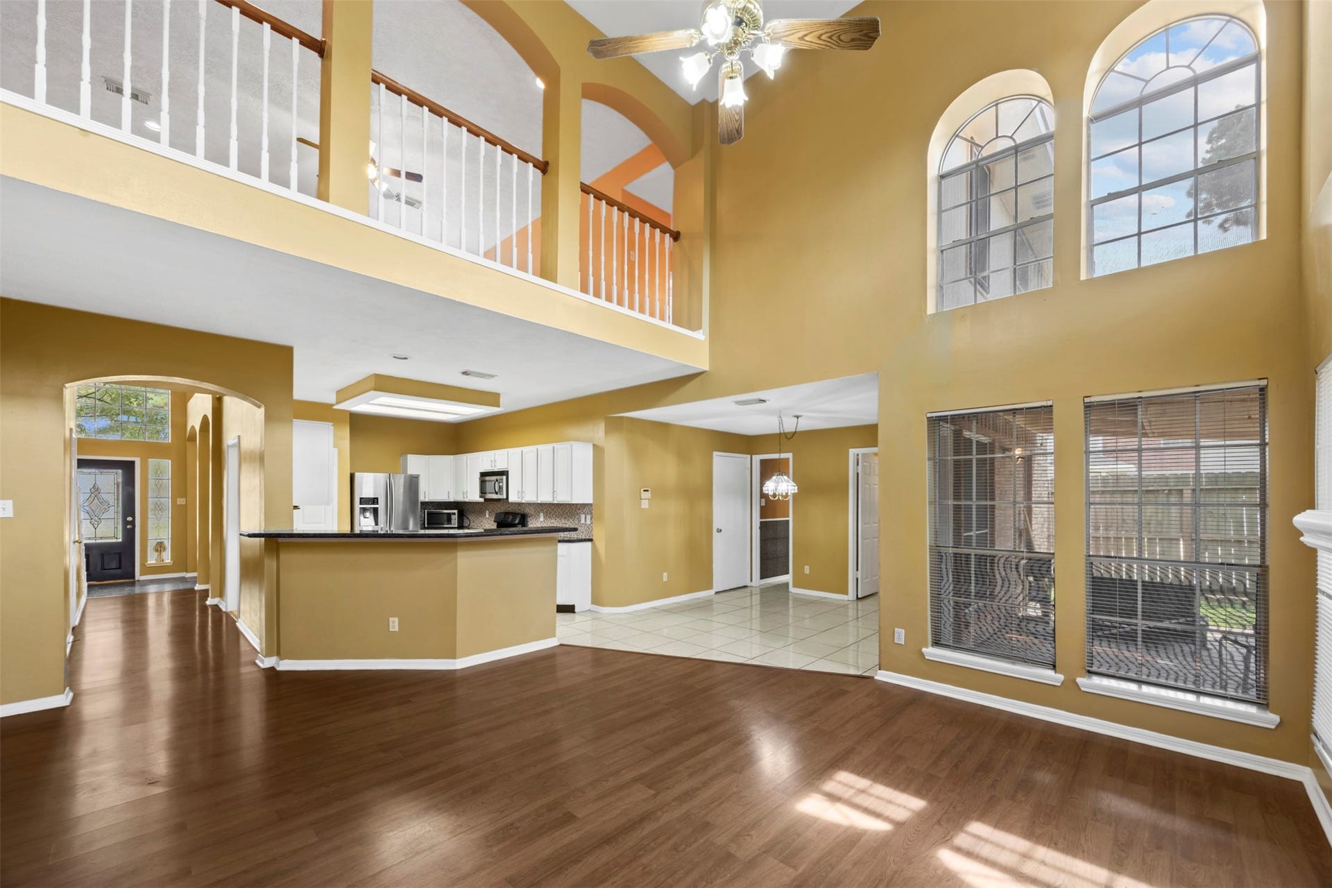 19119 Timber Trace Drive, Humble, TX 77346 Stunning two-story living area with soaring ceilings, abundant natural light from large arched windows, and an open layout that seamlessly connects to the modern kitchen and dining space.