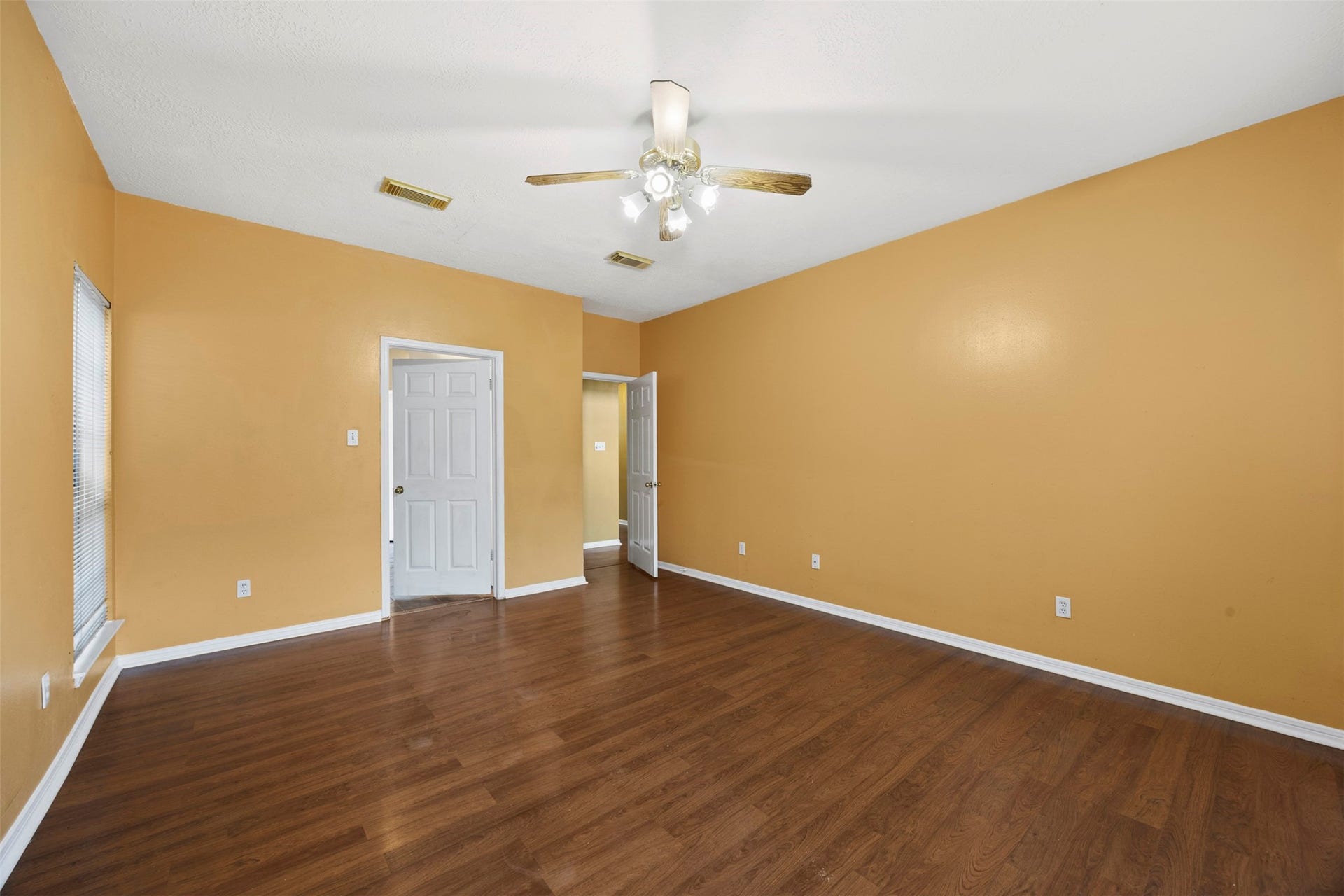 19119 Timber Trace Drive, Humble, TX 77346 Spacious room with warm-toned walls and rich wood flooring, featuring a ceiling fan and ample natural light from the window.