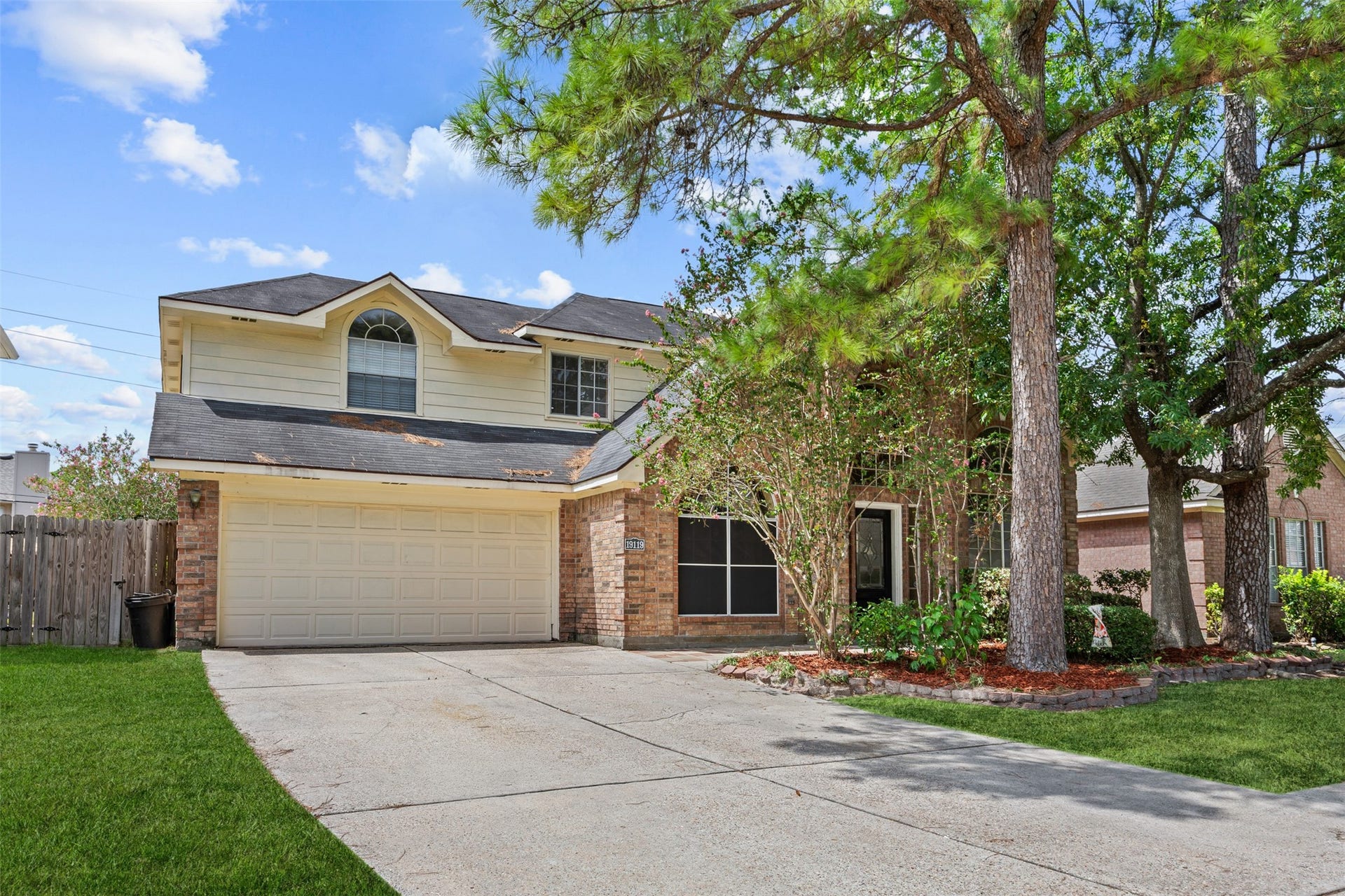 19119 Timber Trace Drive, Humble, TX 77346 Charming two-story home with a spacious driveway, nestled among mature trees. The exterior features a classic brick facade and a welcoming front entry.