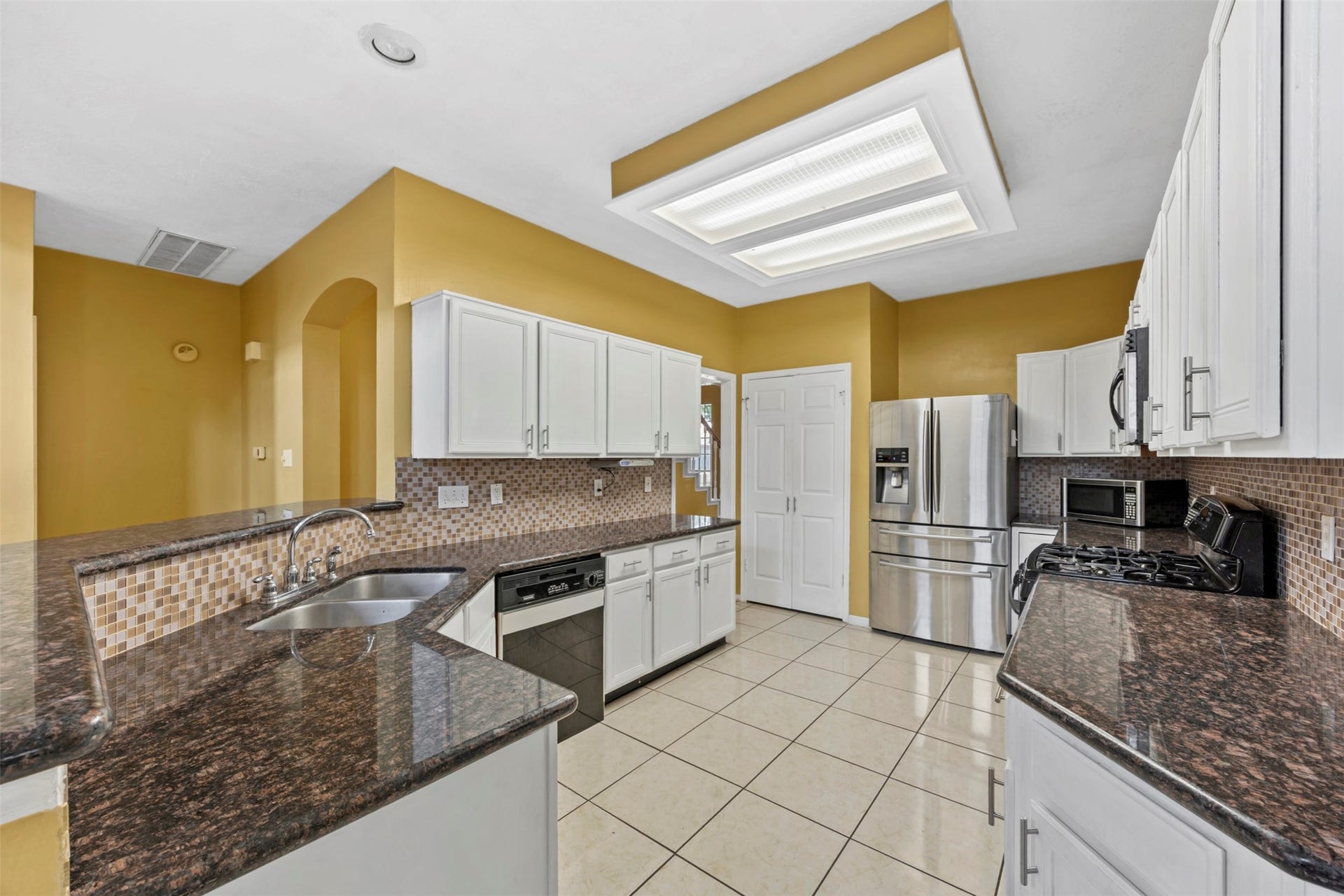 19119 Timber Trace Drive, Humble, TX 77346 Spacious kitchen with sleek granite countertops, modern stainless steel appliances, and ample white cabinetry, all complemented by a stylish tile backsplash and recessed lighting.