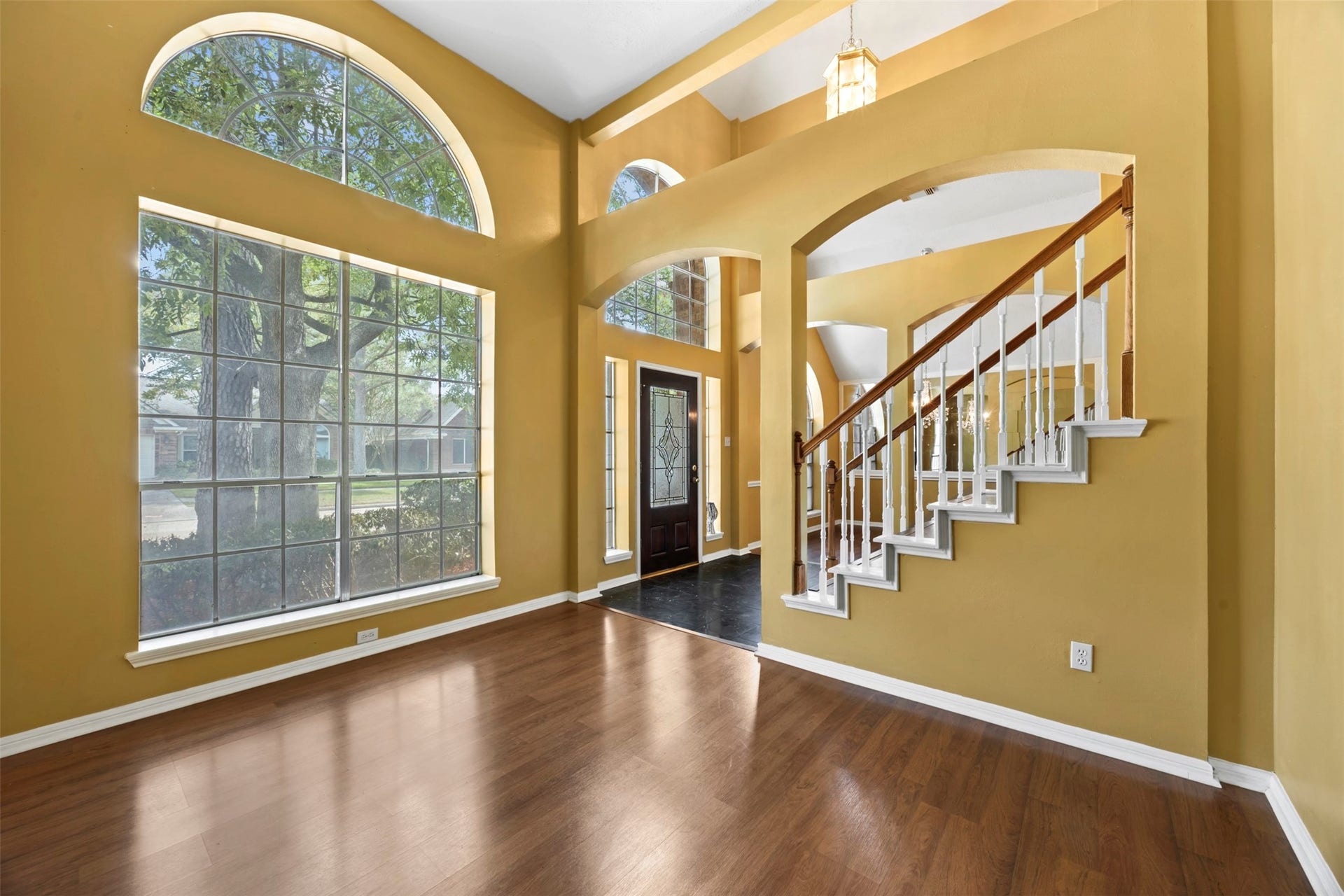 19119 Timber Trace Drive, Humble, TX 77346 Bright and spacious foyer with large arched windows, rich wood flooring, and a stylish staircase leading to the upper level.