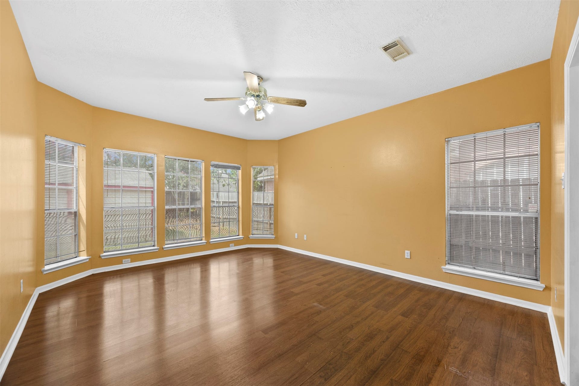 19119 Timber Trace Drive, Humble, TX 77346 Bright and spacious living area featuring large windows, warm-toned walls, and elegant wood flooring, perfect for relaxing or entertaining.