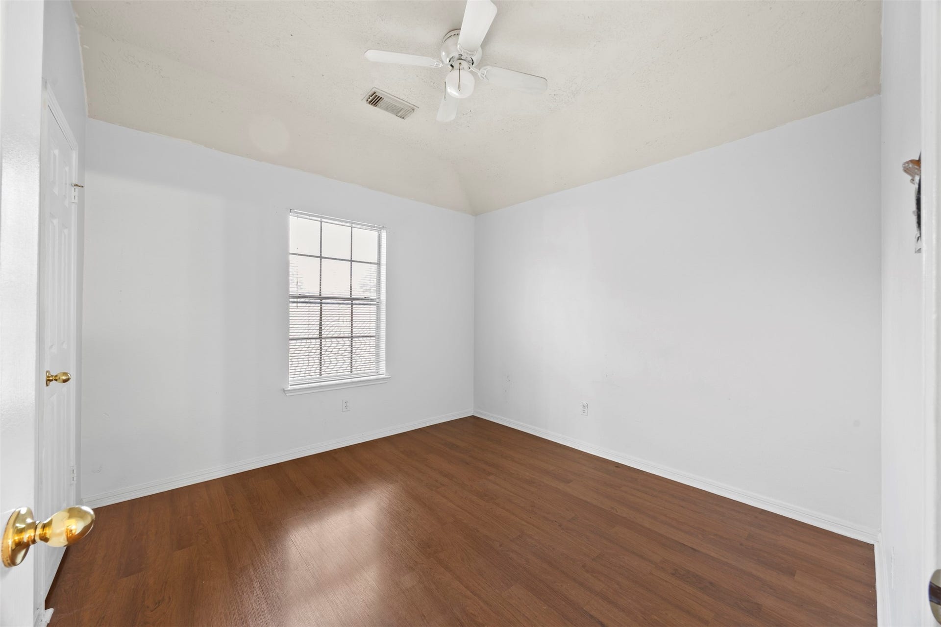 19119 Timber Trace Drive, Humble, TX 77346 Spacious room with warm wood flooring, fresh white walls, and natural light streaming through a large window, complemented by a ceiling fan for comfort.
