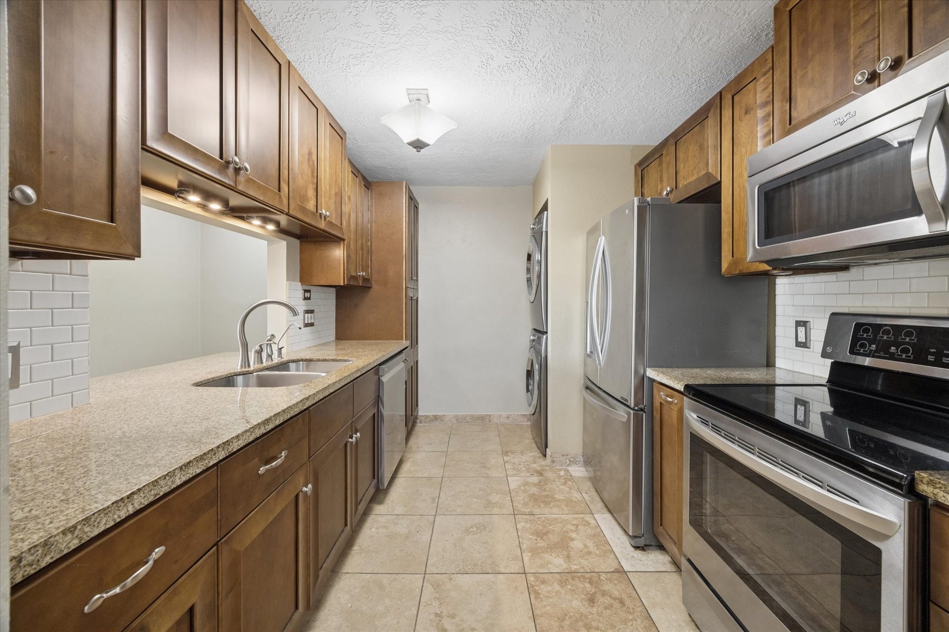1915 Augusta Drive, #43, Houston, TX 77057 Galley-style kitchen featuring rich wood cabinetry, granite countertops, stainless steel appliances, and a functional layout with plenty of storage and prep space.