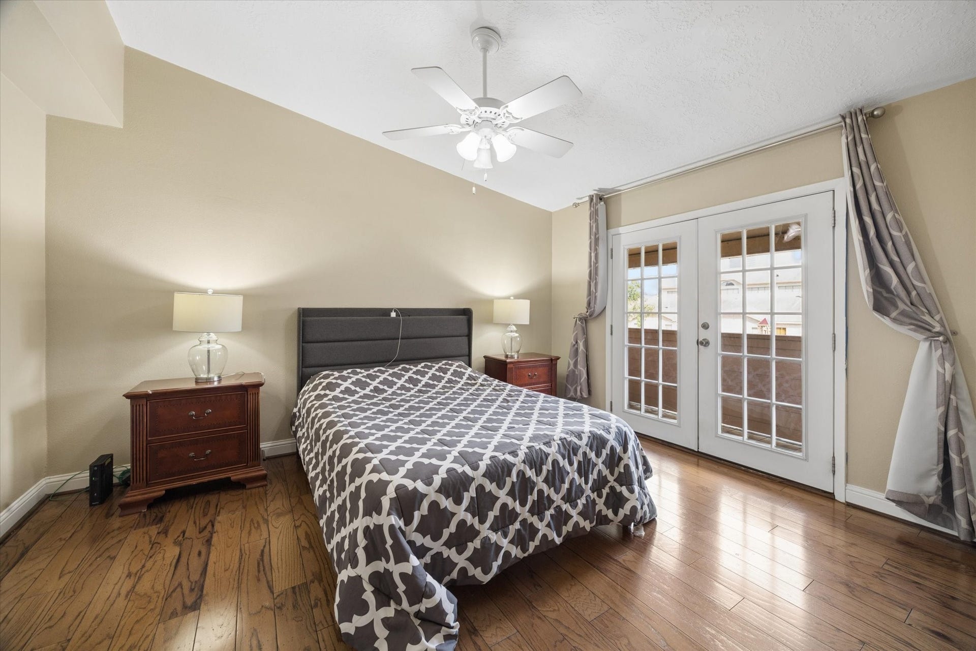 1915 Augusta Drive, #43, Houston, TX 77057 Spacious primary bedroom with hardwood floors, neutral finishes, ceiling fan, and French doors that bring in natural light and add architectural charm.