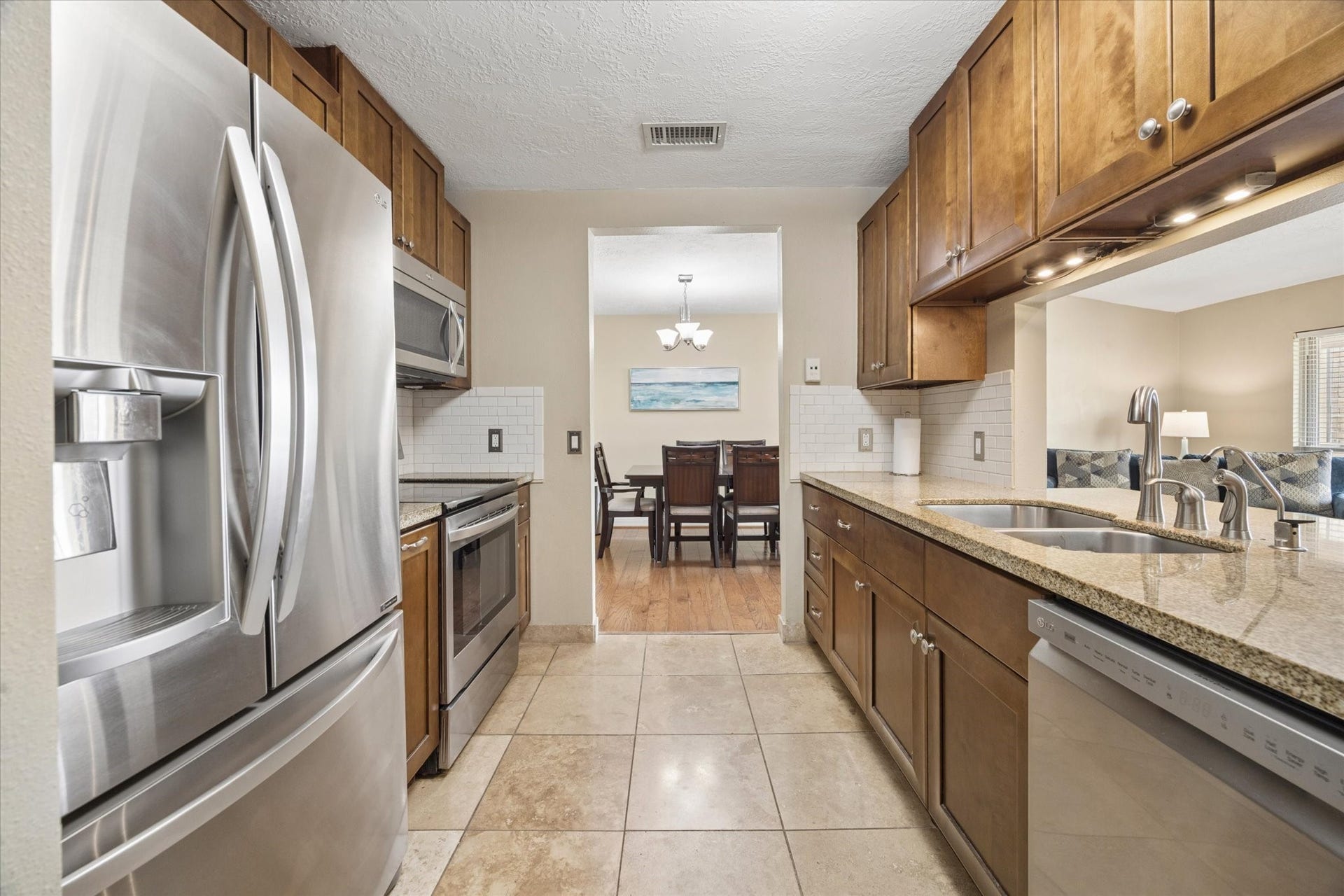 1915 Augusta Drive, #43, Houston, TX 77057 Updated galley kitchen with granite countertops, rich wood cabinetry, stainless steel appliances, and excellent storage, with an open sightline toward the adjoining living and dining areas.