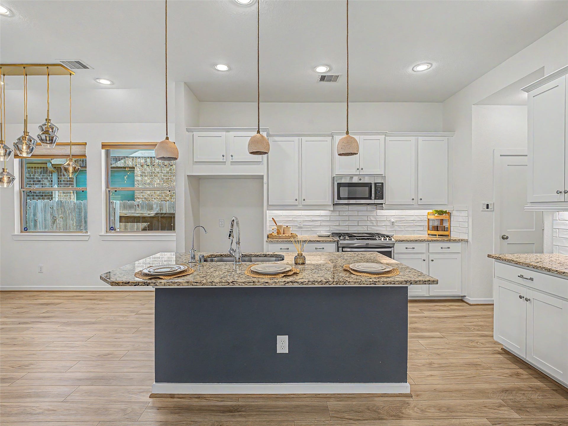 6019 Dovetail Cliff Court, Katy, TX 77493 Crisp white cabinetry with modern pull-handles line the perimeter walls and surround the stainless steel gas range, oven, and built-in microwave, all accented by a classic white subway tile backsplash with under-cabinet task lighting.