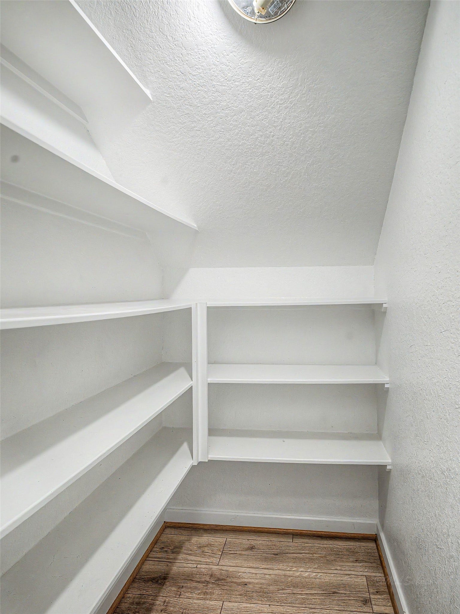 6019 Dovetail Cliff Court, Katy, TX 77493 This spacious walk-in pantry maximizes storage and organization directly off the main kitchen area. Designed with practical efficiency in mind, it features custom wrapped multi-tiered white shelving that makes full use of the room's height and corners.