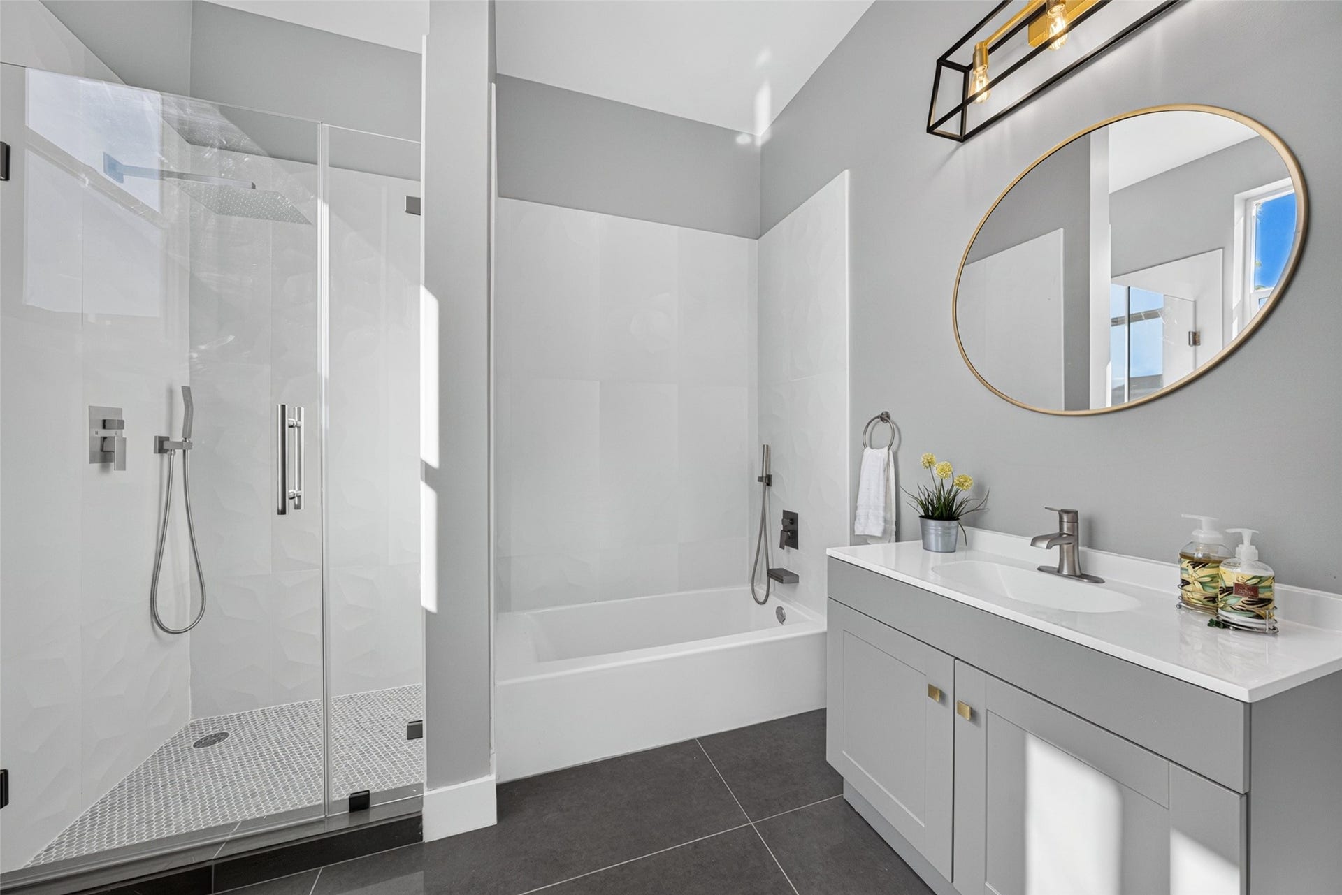 Modern first-floor bathroom featuring a sleek round mirror, clean white subway tile, and a stylish glass-enclosed shower.