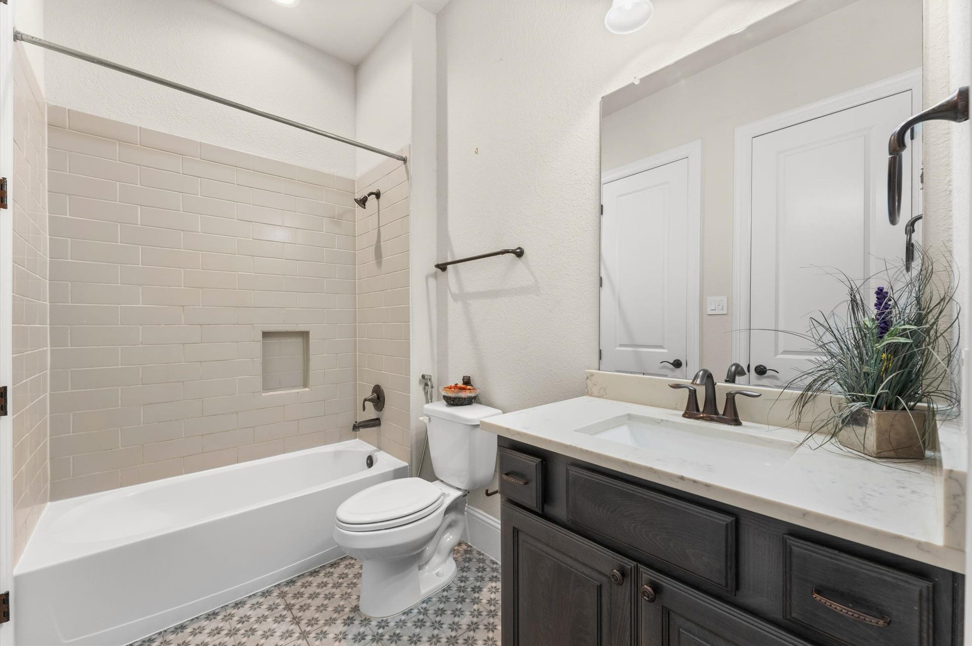 118 Stadium Drive, Sugar Land, TX 77498 Charming bathroom featuring a classic subway tile shower, elegant dark wood vanity with a marble countertop, and stylish patterned floor tiles.