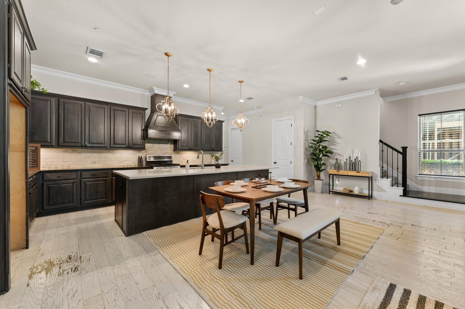 118 Stadium Drive, Sugar Land, TX 77498 Spacious open-concept kitchen and dining area featuring elegant dark cabinetry, modern lighting fixtures, and a large island perfect for entertaining.
