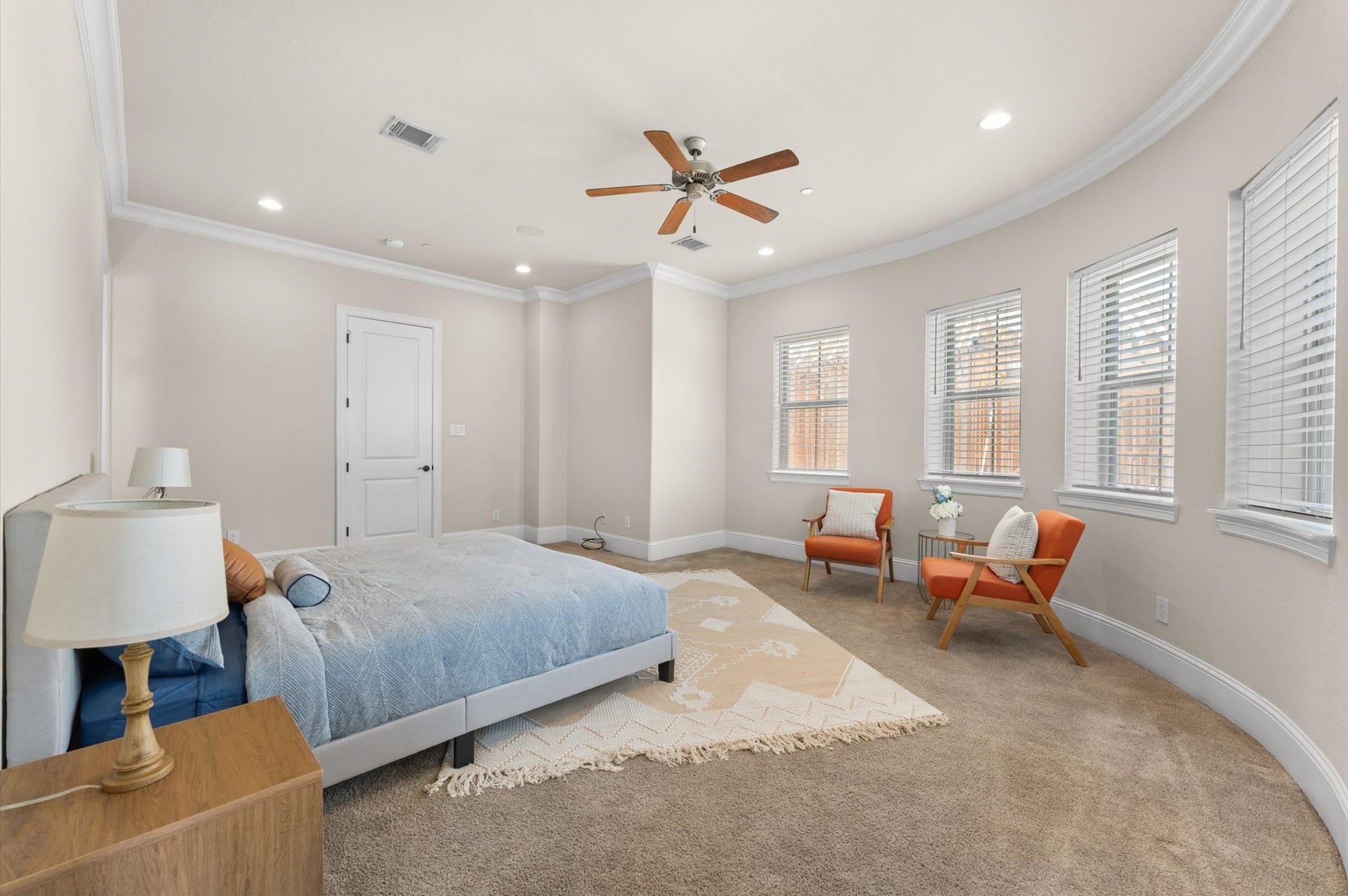 118 Stadium Drive, Sugar Land, TX 77498 Spacious bedroom featuring a cozy bed, elegant ceiling fan, and ample natural light from multiple windows, complemented by a stylish seating area. Bay windows has the view of stadium Fireworks.