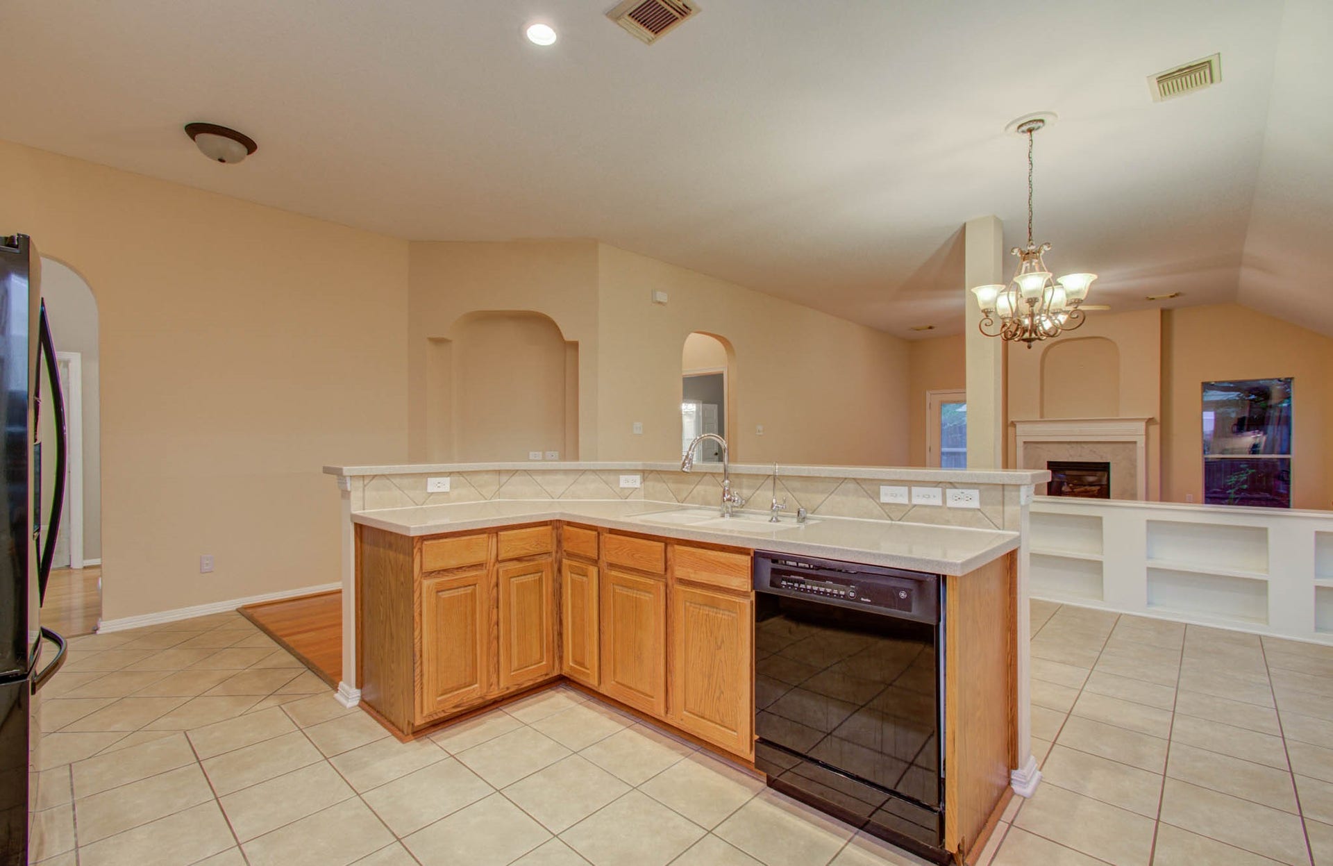 14403 Red Tailed Hawk Lane, Houston, TX 77044 Spacious open-concept kitchen with a central island, ample counter space, and a view of the cozy living area featuring a fireplace and built-in shelving.