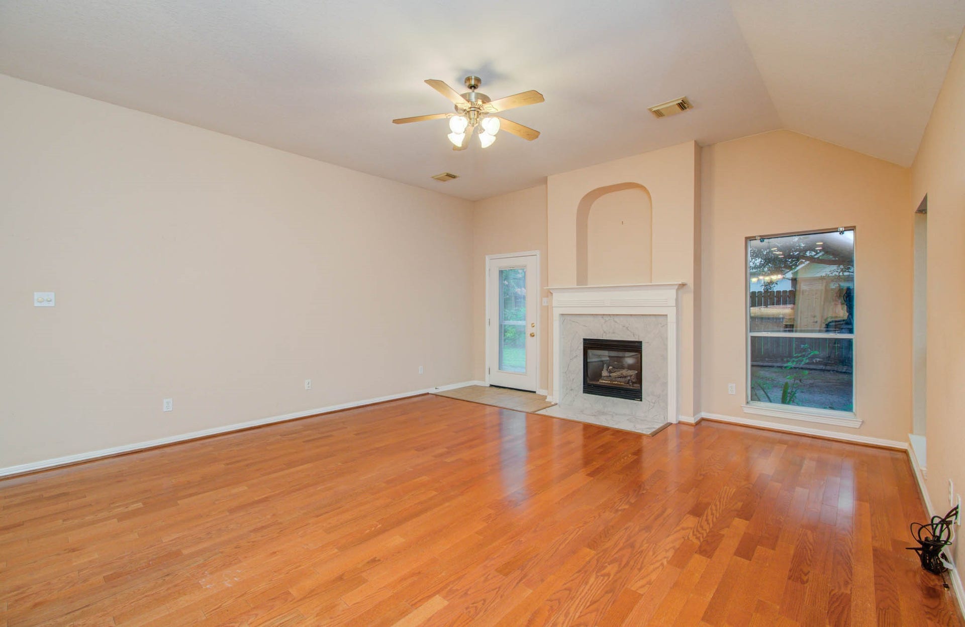 14403 Red Tailed Hawk Lane, Houston, TX 77044 Spacious living room featuring elegant hardwood floors, a cozy fireplace with a classic mantle, and abundant natural light pouring in through large windows and a glass door.