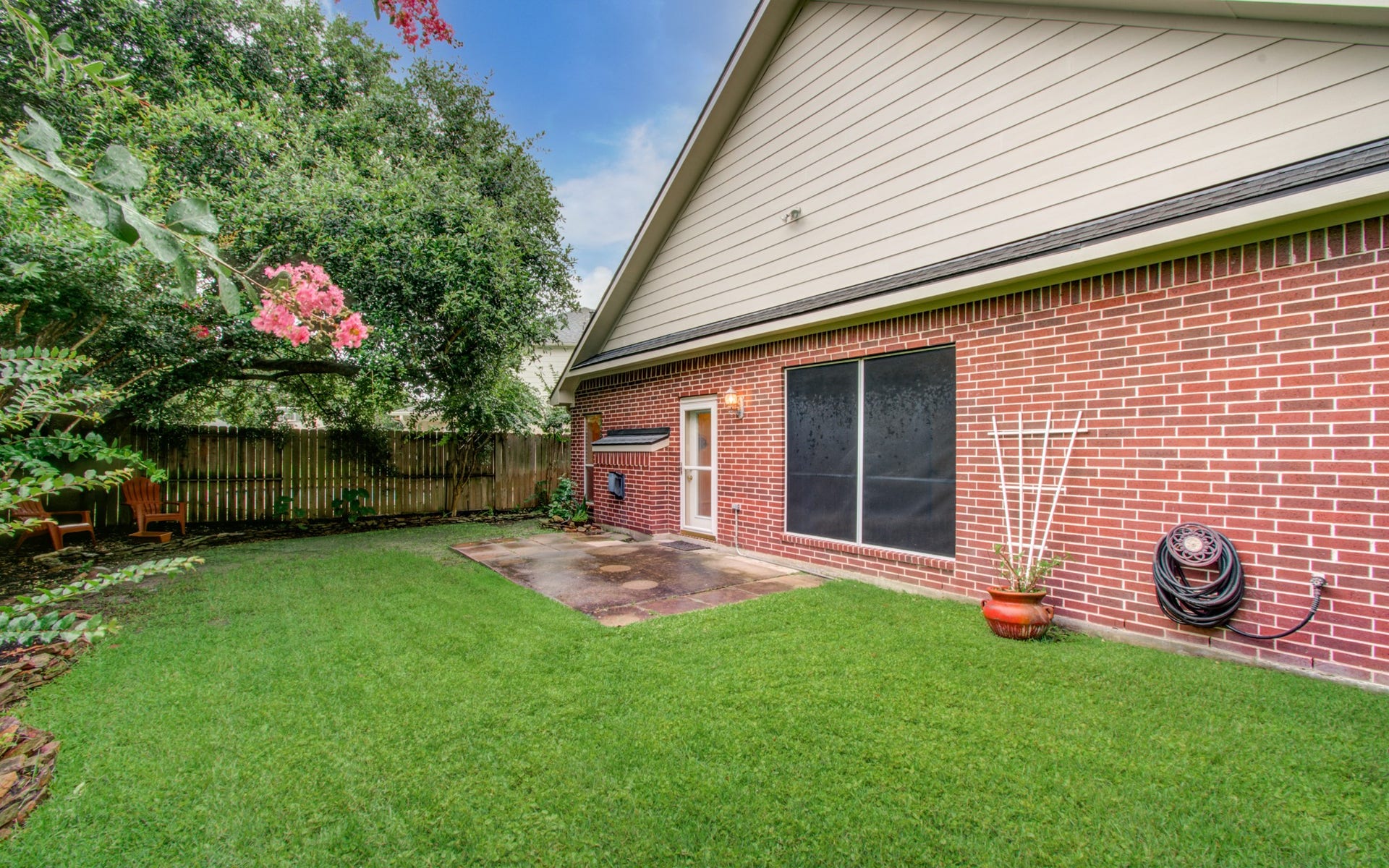 14403 Red Tailed Hawk Lane, Houston, TX 77044 Charming backyard with lush green lawn, mature trees, and a cozy patio area perfect for relaxation or entertaining.