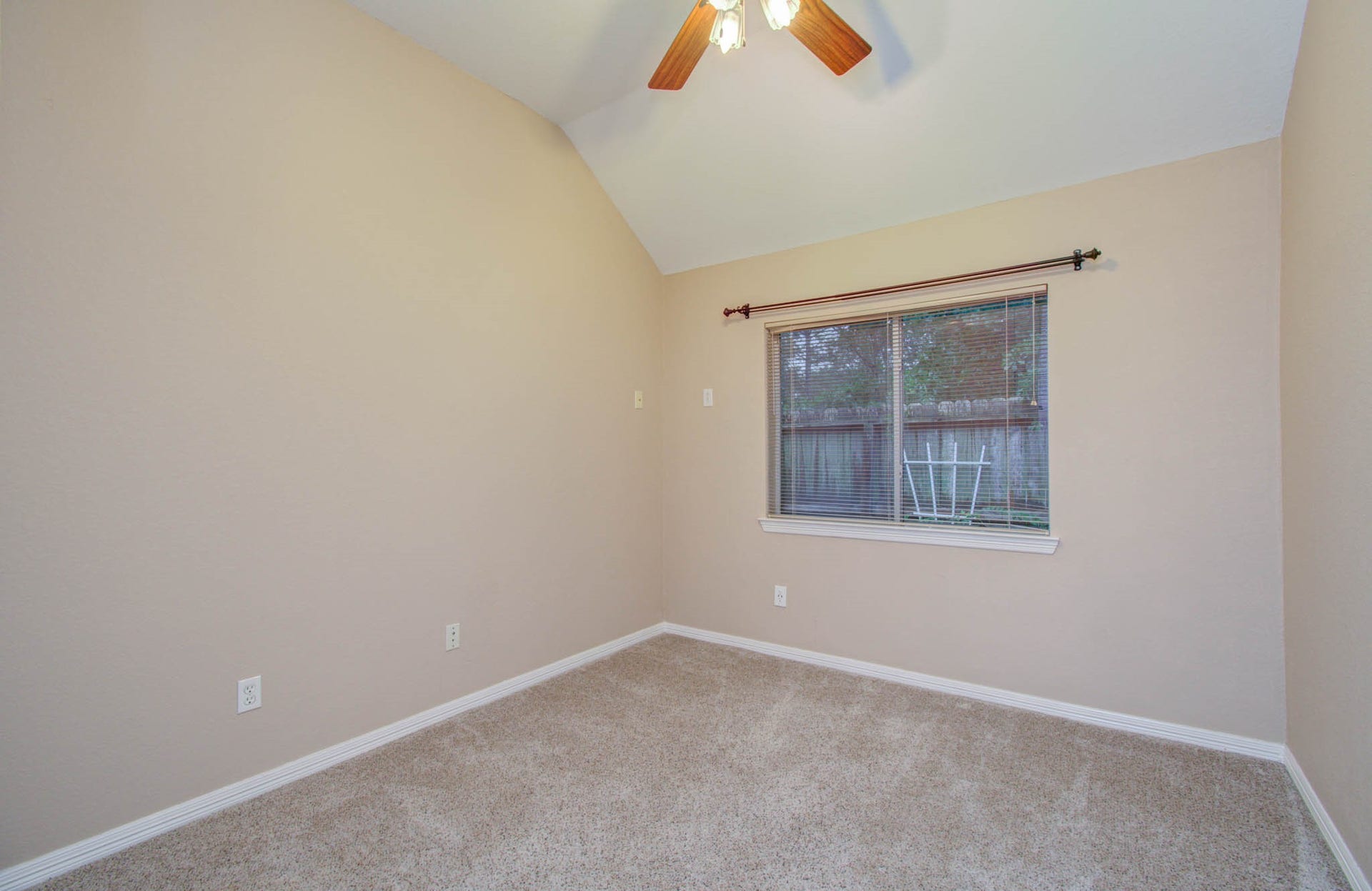 14403 Red Tailed Hawk Lane, Houston, TX 77044 Cozy bedroom with soft carpeting, neutral walls, and a ceiling fan, offering a peaceful view through a large window.