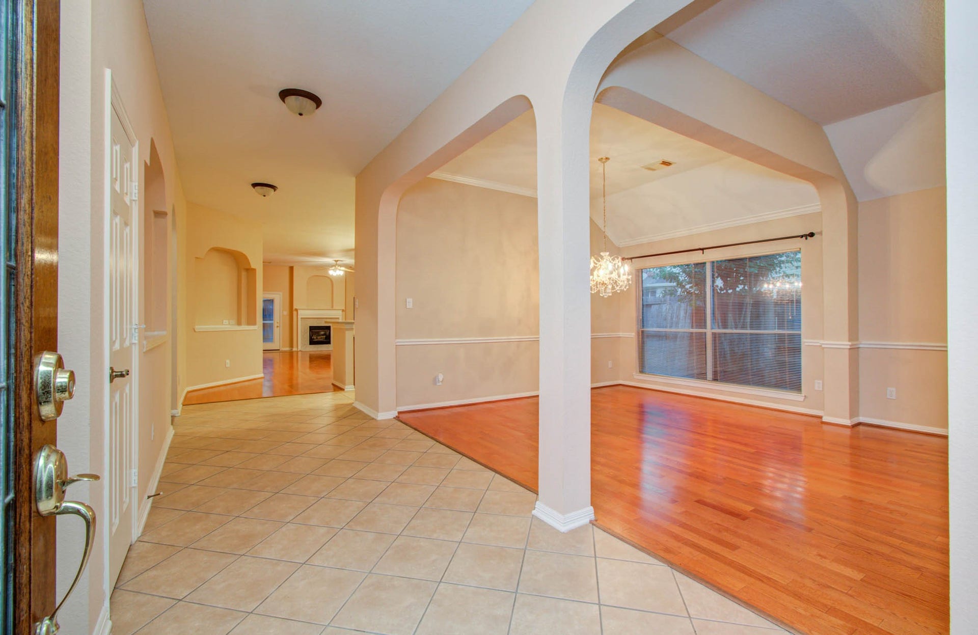 14403 Red Tailed Hawk Lane, Houston, TX 77044 Elegant entryway with tile flooring and archways, seamlessly leading to a bright dining area featuring hardwood floors and a stunning chandelier.