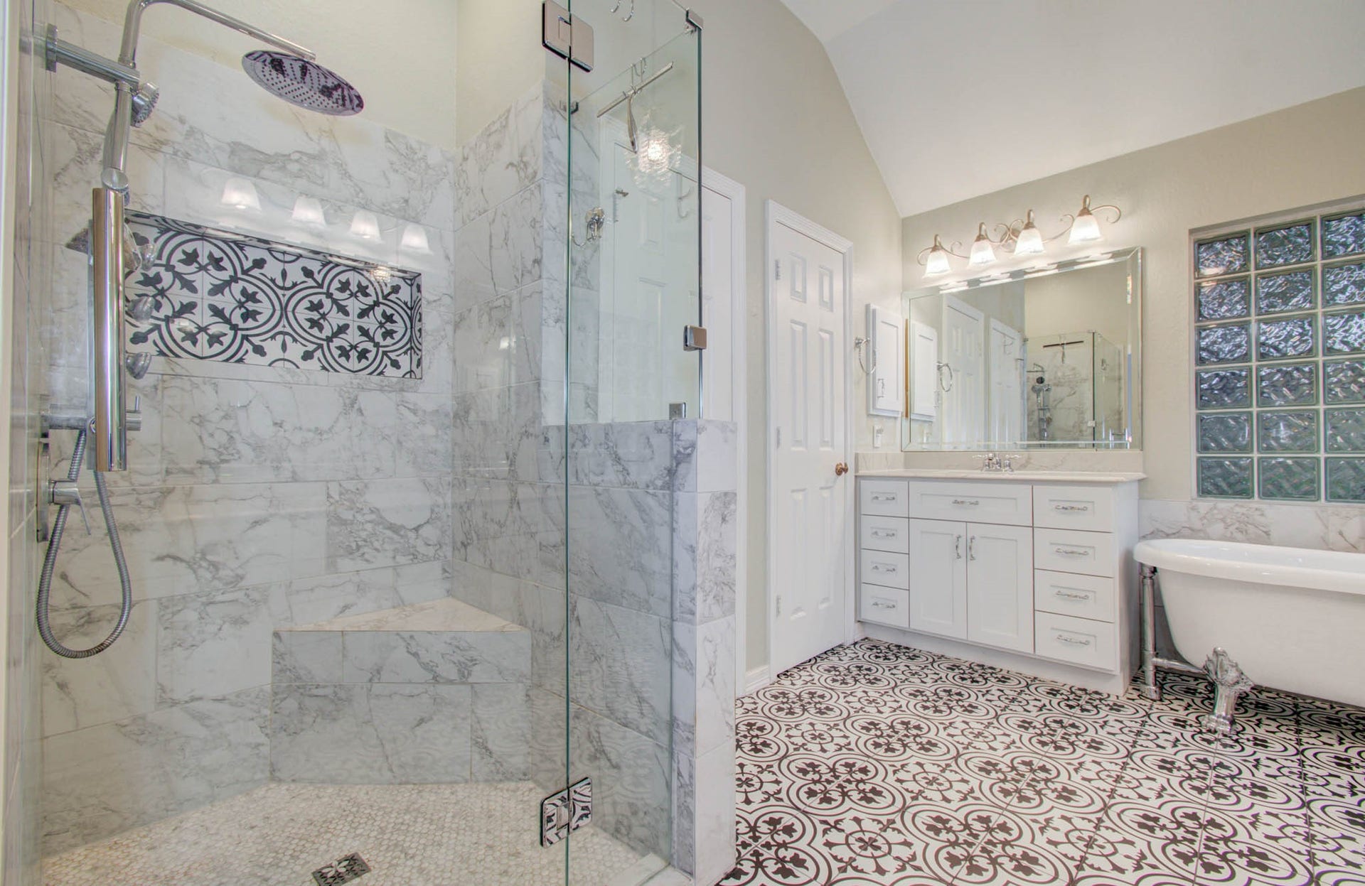 14403 Red Tailed Hawk Lane, Houston, TX 77044 Elegant bathroom featuring a spacious glass-enclosed marble shower, intricate tile flooring, and a classic clawfoot tub, complemented by a stylish vanity with ample storage.