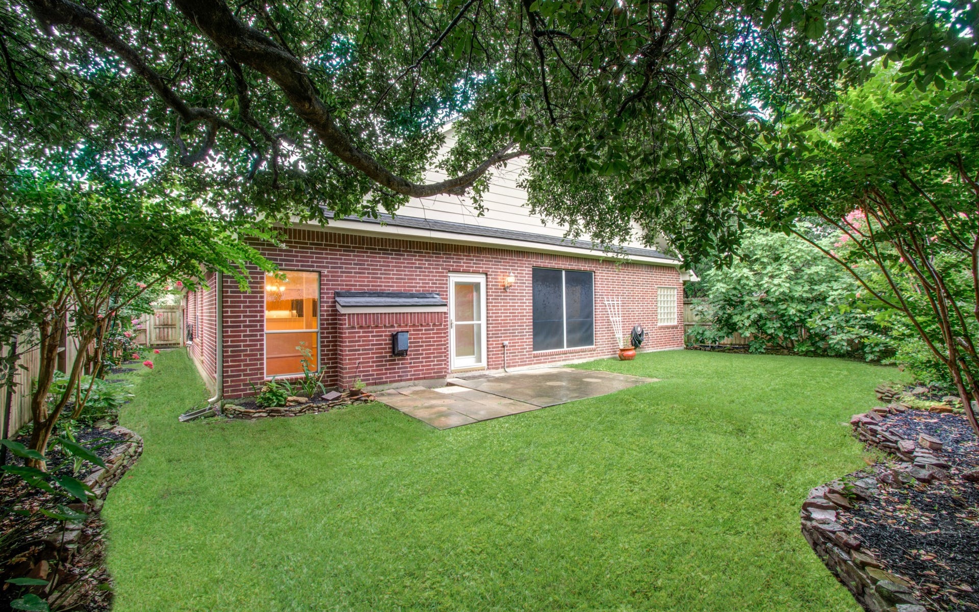 14403 Red Tailed Hawk Lane, Houston, TX 77044 Charming backyard with lush greenery and a spacious patio, perfect for outdoor entertaining.