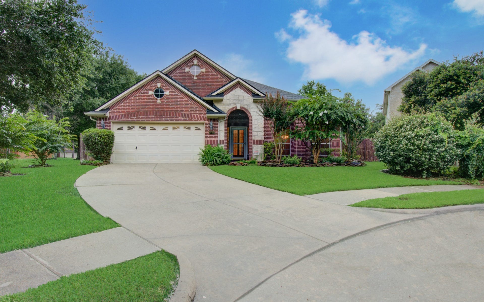 14403 Red Tailed Hawk Lane, Houston, TX 77044 Charming brick home with a welcoming arched entryway, beautifully landscaped front yard, and a spacious two-car garage, nestled in a serene neighborhood.