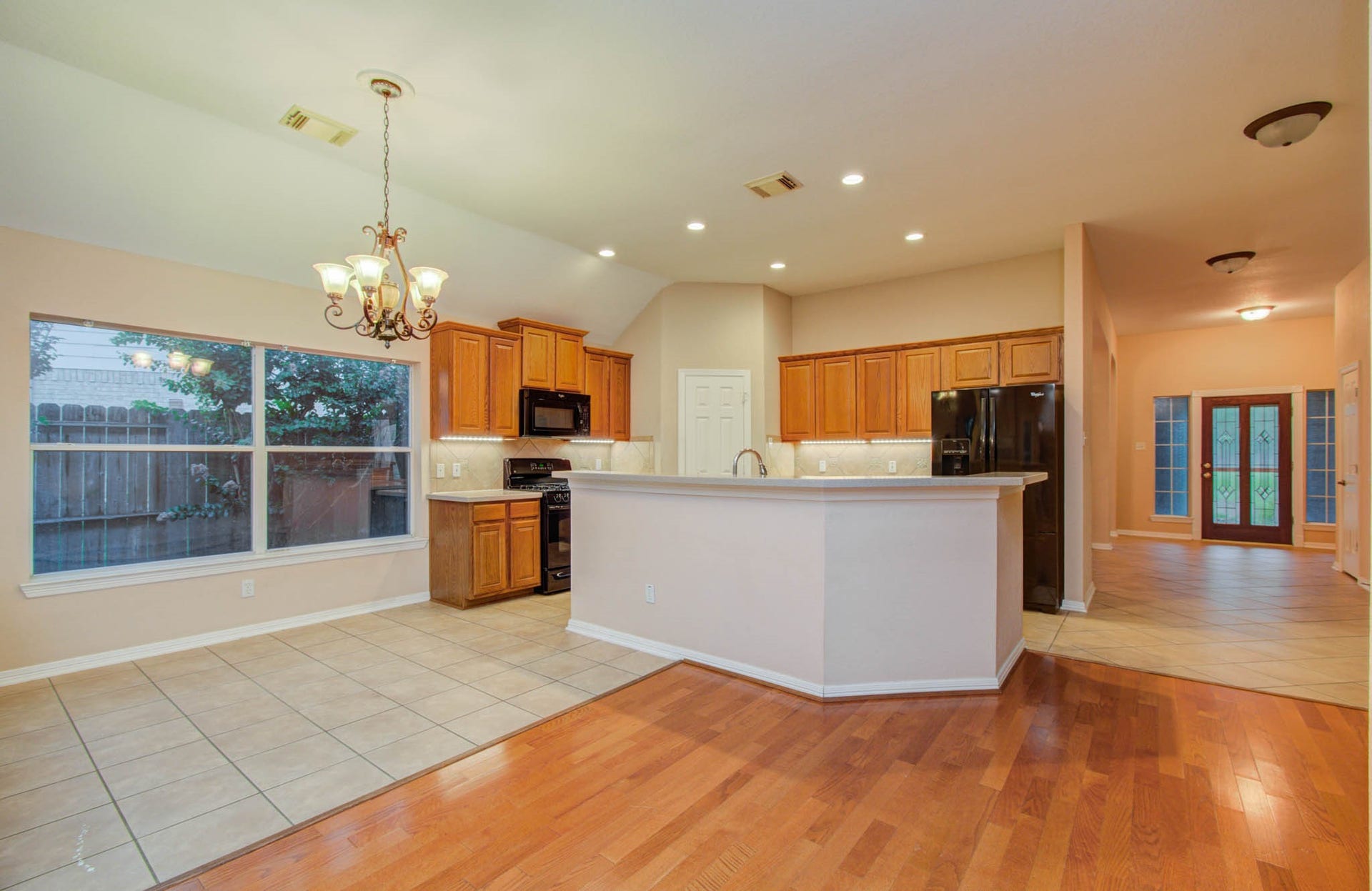 14403 Red Tailed Hawk Lane, Houston, TX 77044 Spacious open-concept kitchen with warm wood cabinetry, modern appliances, and a large island, seamlessly flowing into a bright dining area with a charming chandelier.
