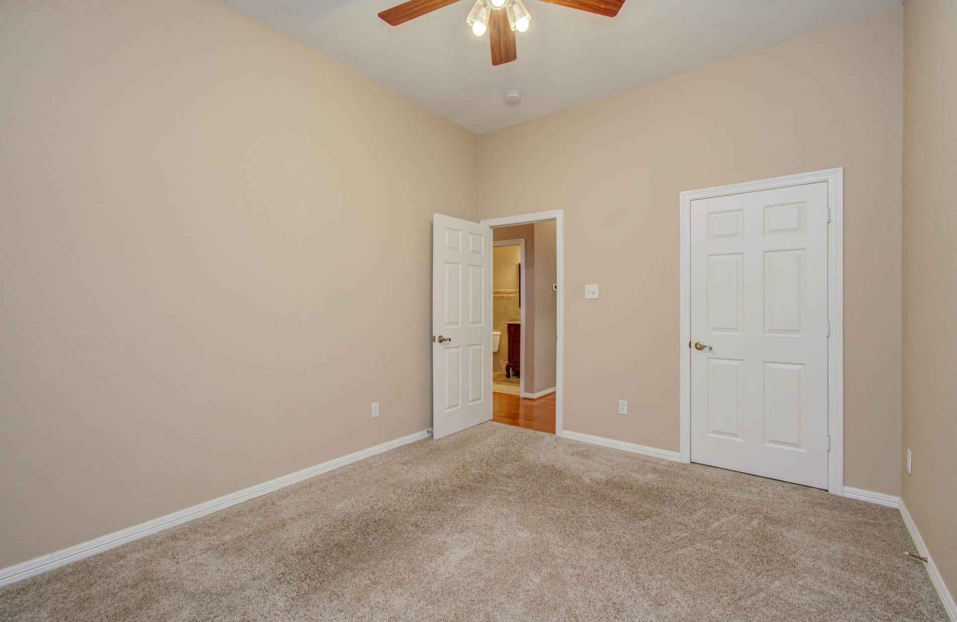 14403 Red Tailed Hawk Lane, Houston, TX 77044 Cozy room with neutral walls, plush carpet, and ceiling fan, offering ample space and two doors for convenient access.