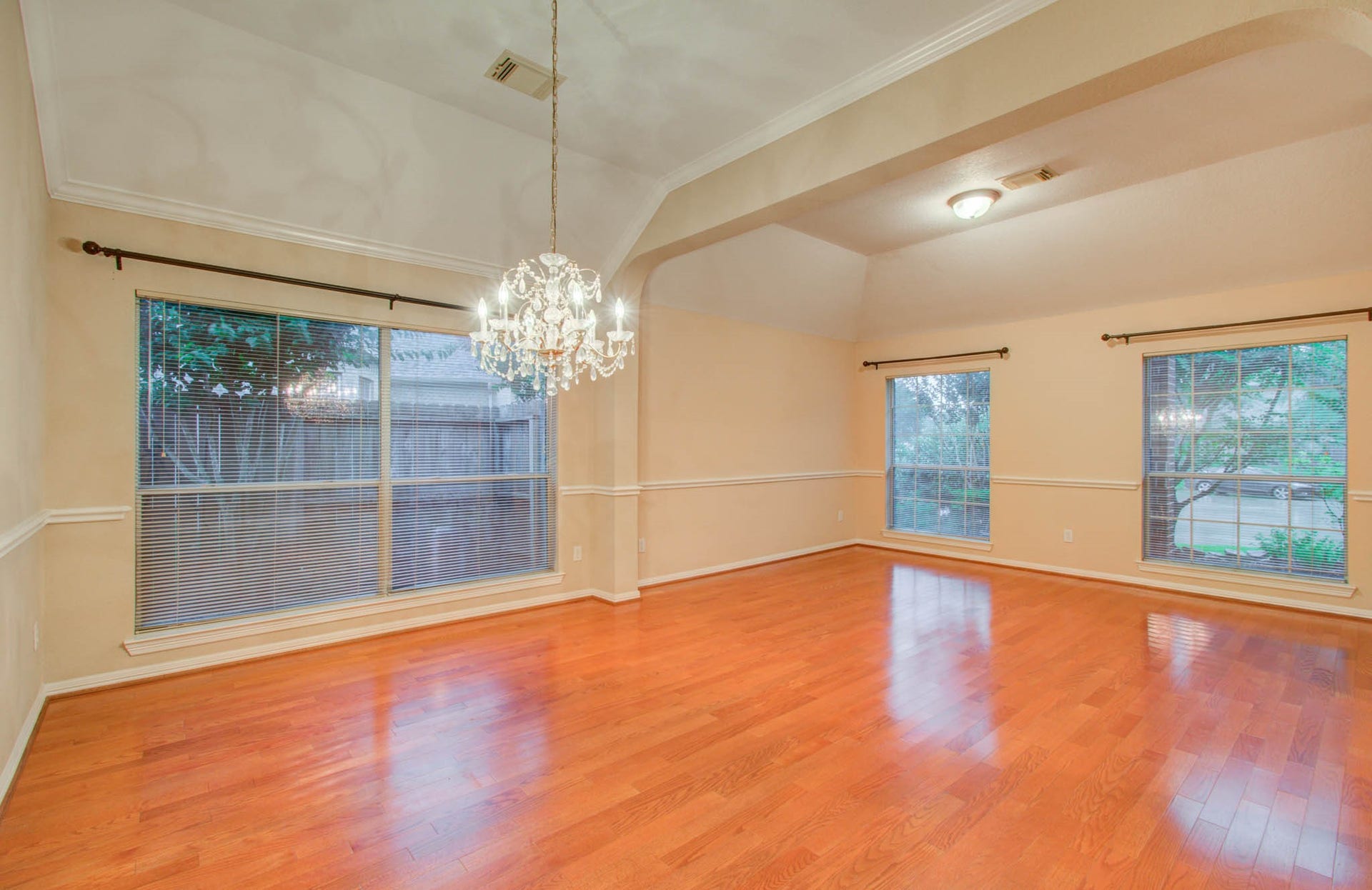 14403 Red Tailed Hawk Lane, Houston, TX 77044 Elegant dining area with rich hardwood floors, abundant natural light from large windows, and a stunning chandelier, perfect for entertaining.