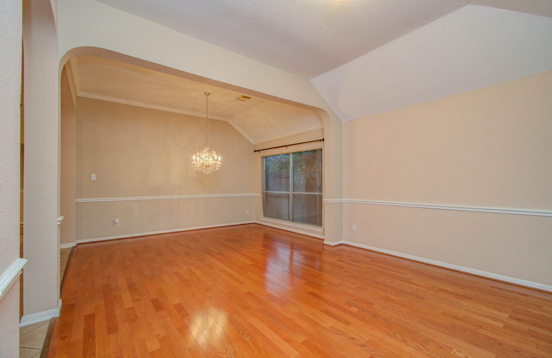 14403 Red Tailed Hawk Lane, Houston, TX 77044 Spacious dining area with elegant hardwood floors, a stylish chandelier, and large windows providing ample natural light.