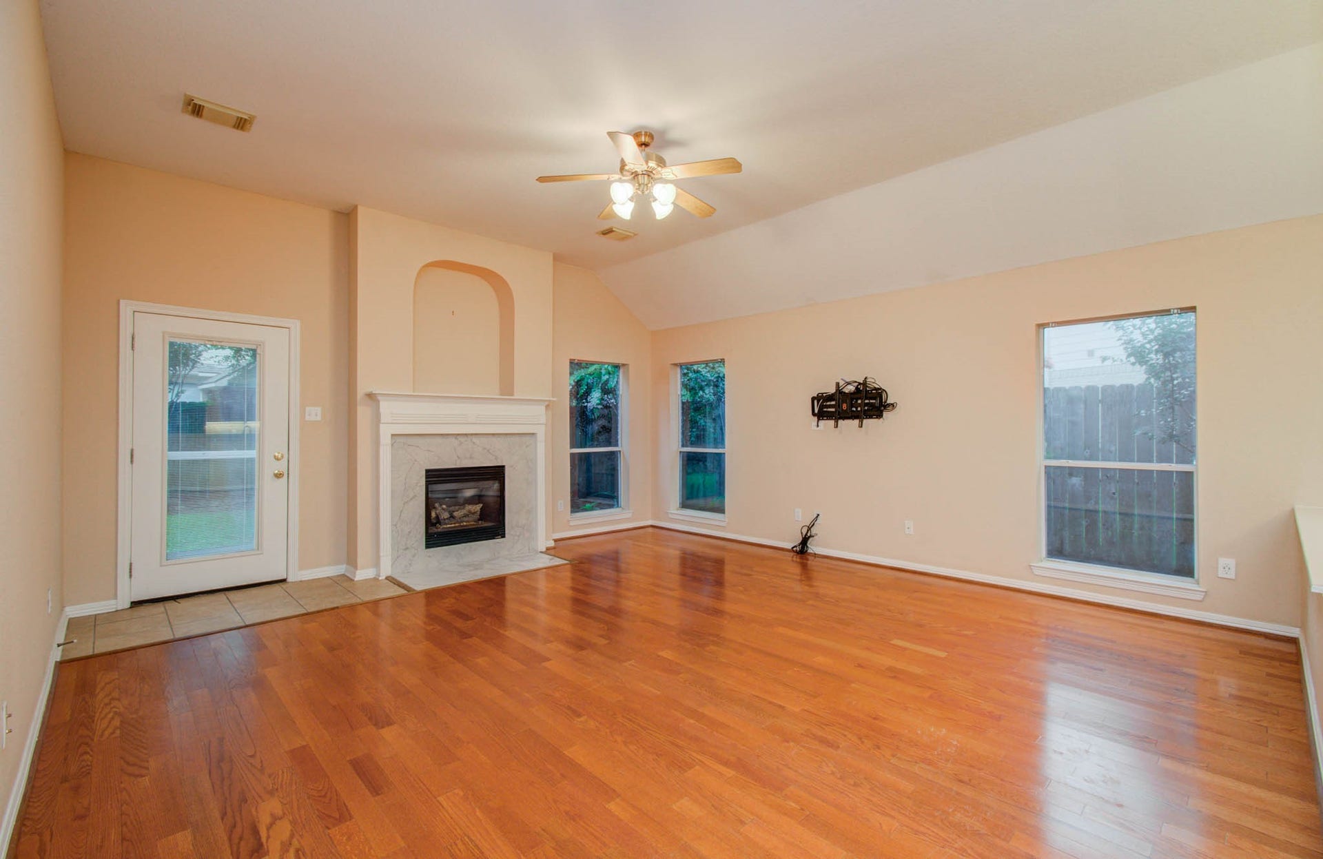 14403 Red Tailed Hawk Lane, Houston, TX 77044 Spacious living room with warm hardwood floors, a cozy fireplace, and abundant natural light from large windows, offering a welcoming atmosphere.