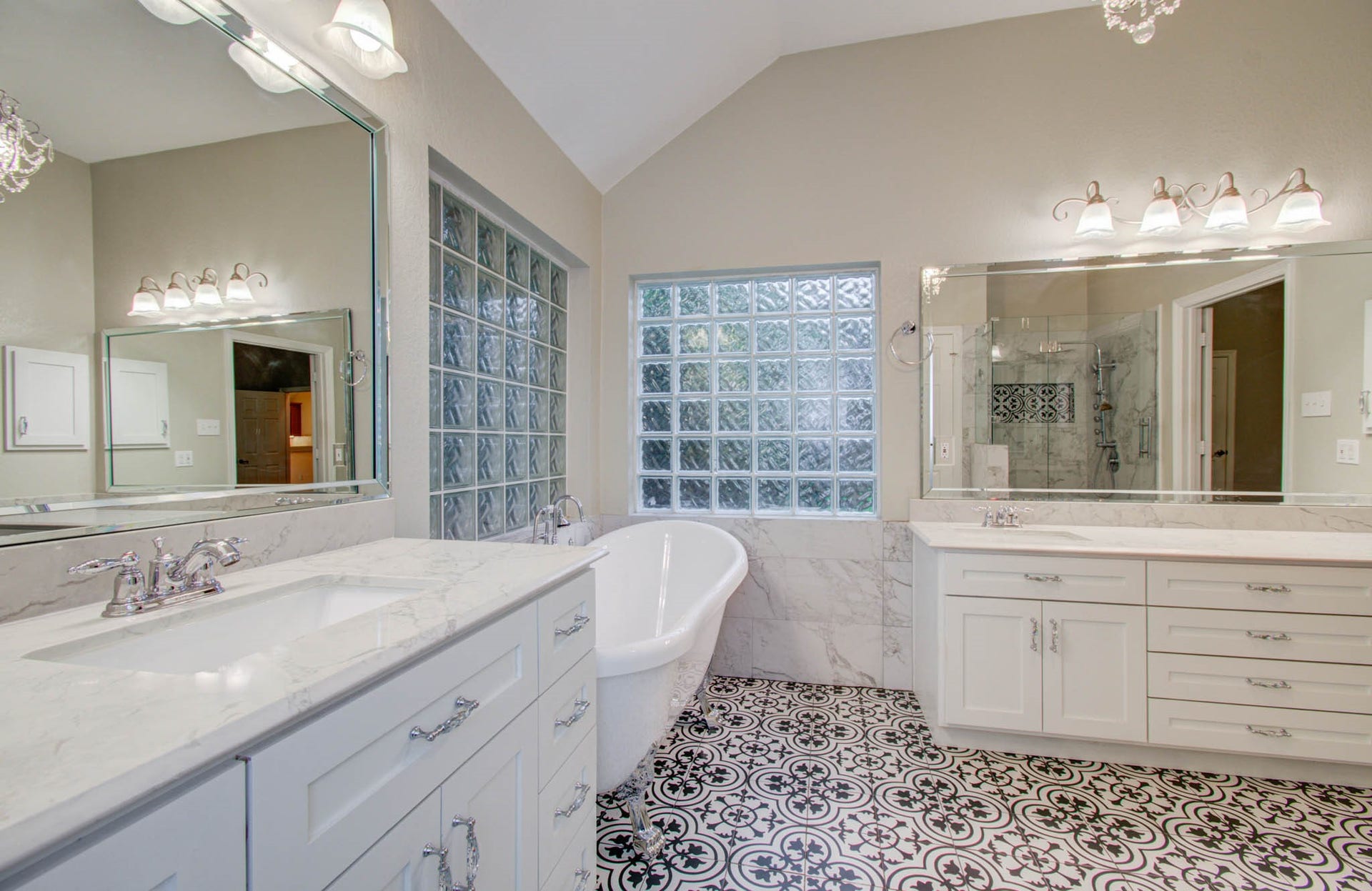 14403 Red Tailed Hawk Lane, Houston, TX 77044 Stunning bathroom featuring a luxurious freestanding tub, elegant dual vanities with marble countertops, and a spacious glass-enclosed shower, all highlighted by stylish patterned tile flooring and ample natural light.