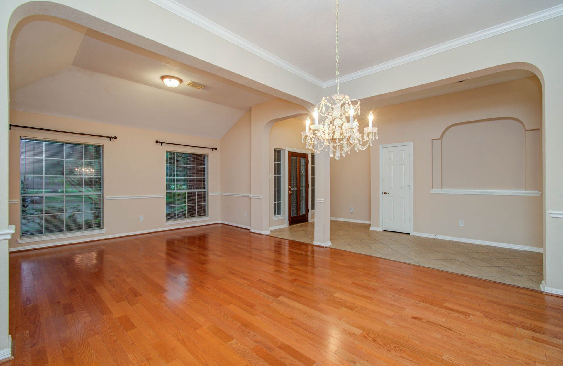 14403 Red Tailed Hawk Lane, Houston, TX 77044 Elegant open living space featuring gleaming hardwood floors, a stunning chandelier, and large windows providing ample natural light.
