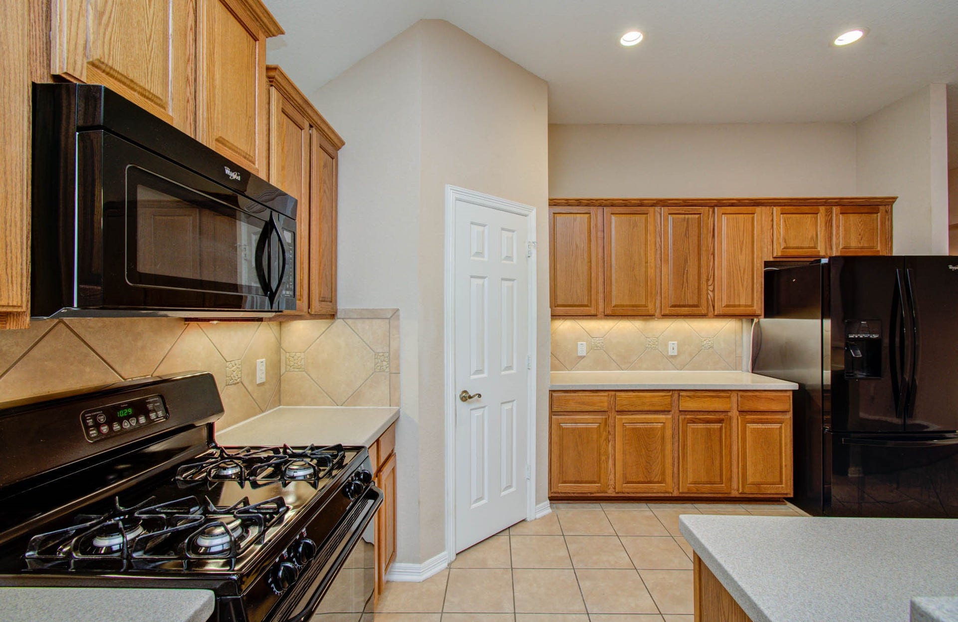 14403 Red Tailed Hawk Lane, Houston, TX 77044 Spacious kitchen with warm wood cabinetry, sleek black appliances, and ample counter space for cooking and entertaining.