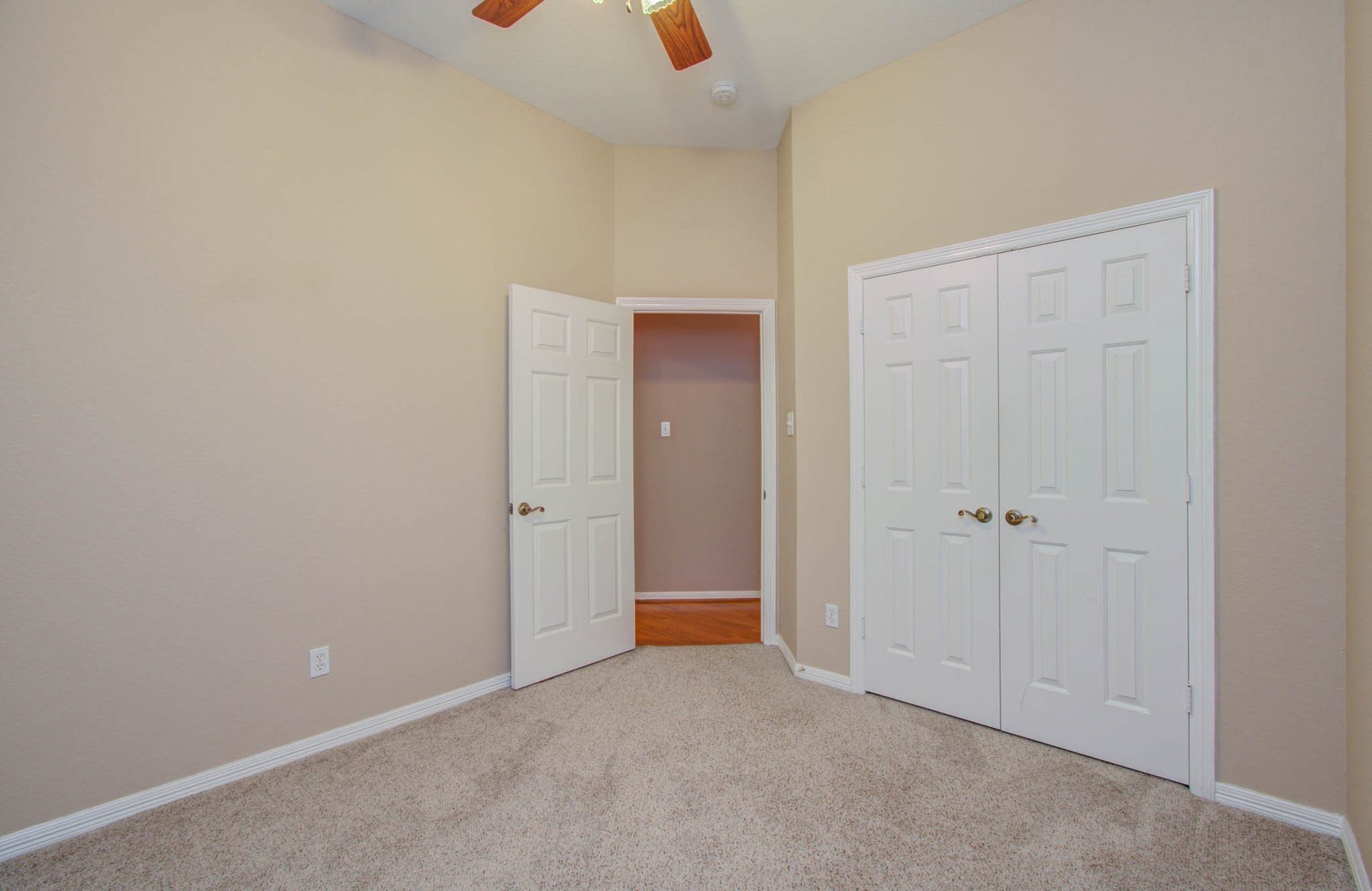 14403 Red Tailed Hawk Lane, Houston, TX 77044 Cozy room with neutral walls, plush carpet, and ample closet space, illuminated by a ceiling fan light.