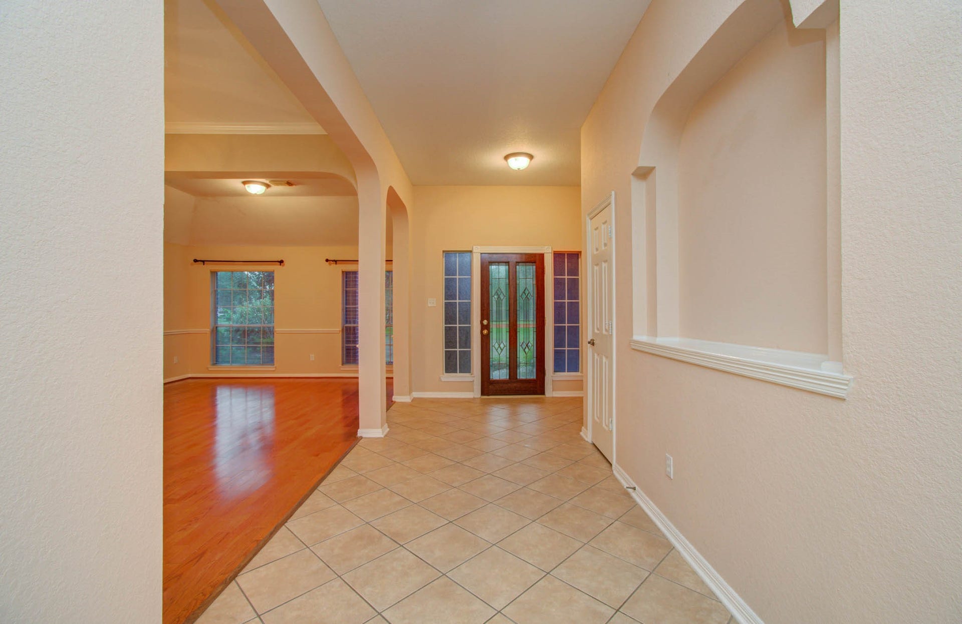 14403 Red Tailed Hawk Lane, Houston, TX 77044 Inviting entryway with elegant tile flooring leads to a spacious living area featuring warm wood floors and large windows for natural light.