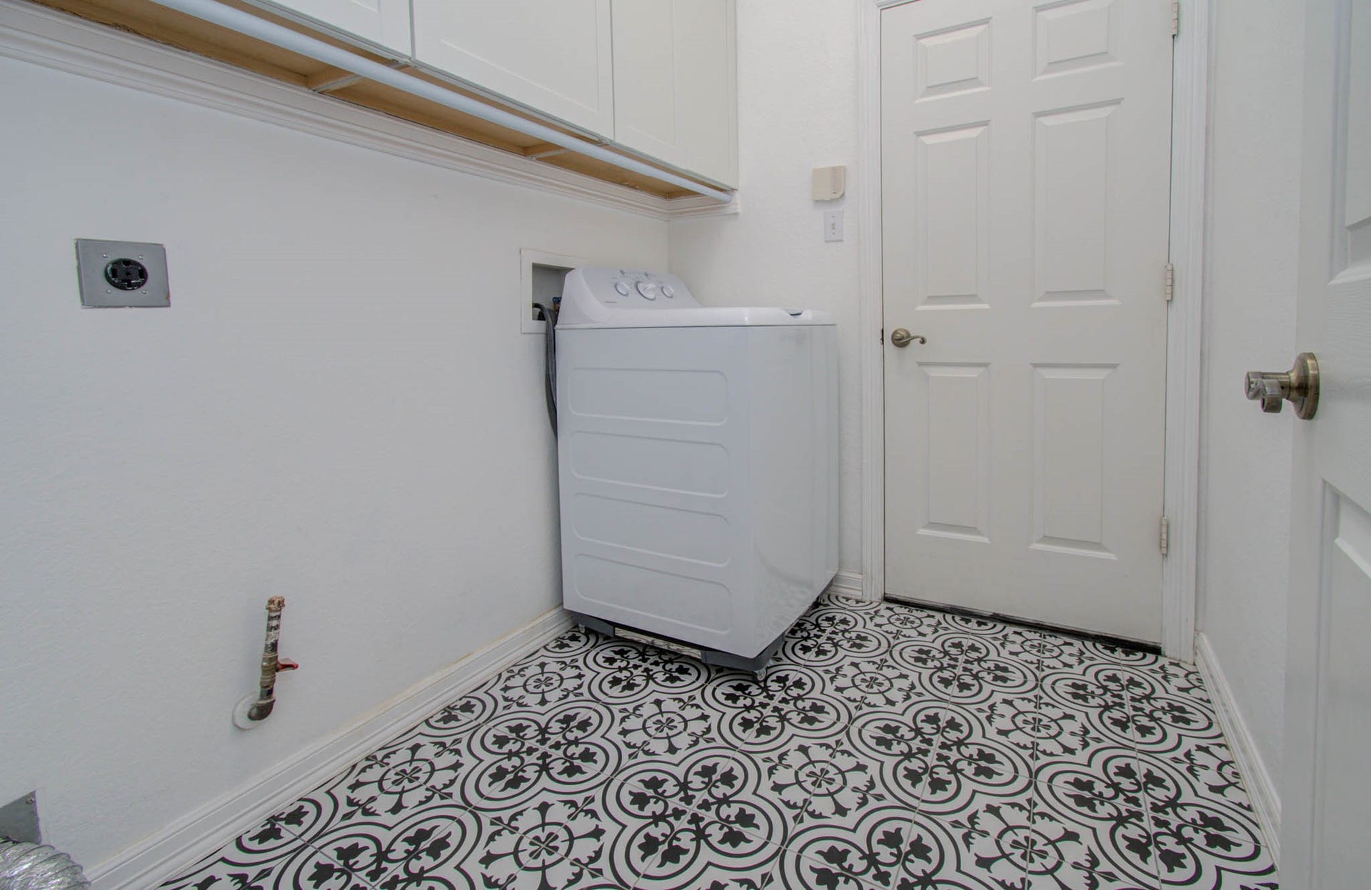 14403 Red Tailed Hawk Lane, Houston, TX 77044 Charming laundry room featuring elegant patterned tile flooring, ample cabinet storage, and a convenient layout.