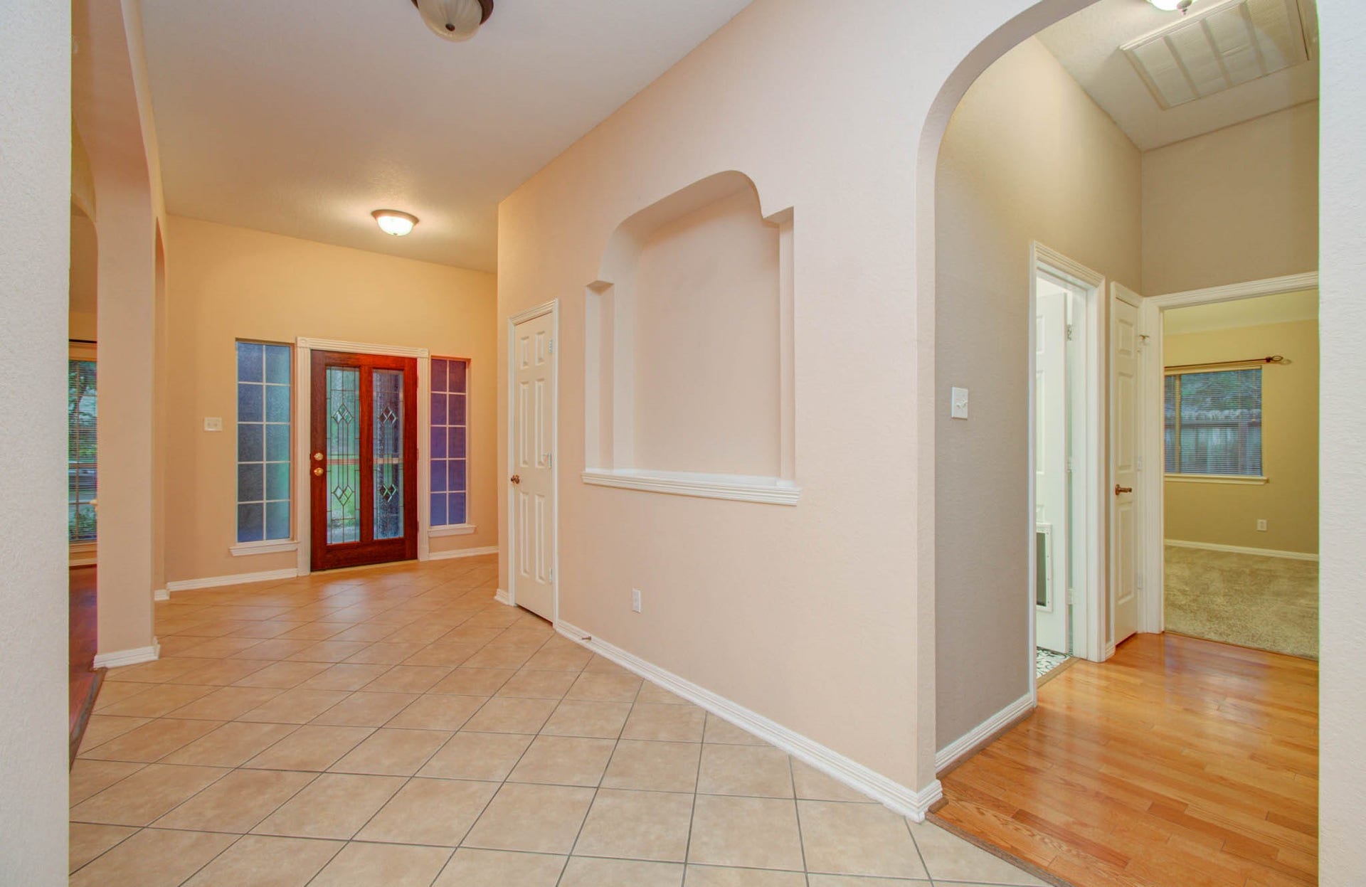 14403 Red Tailed Hawk Lane, Houston, TX 77044 Inviting entryway with elegant tiled flooring, beautiful glass-paneled double doors, and an arched hallway leading to cozy rooms, combining functionality with charm.