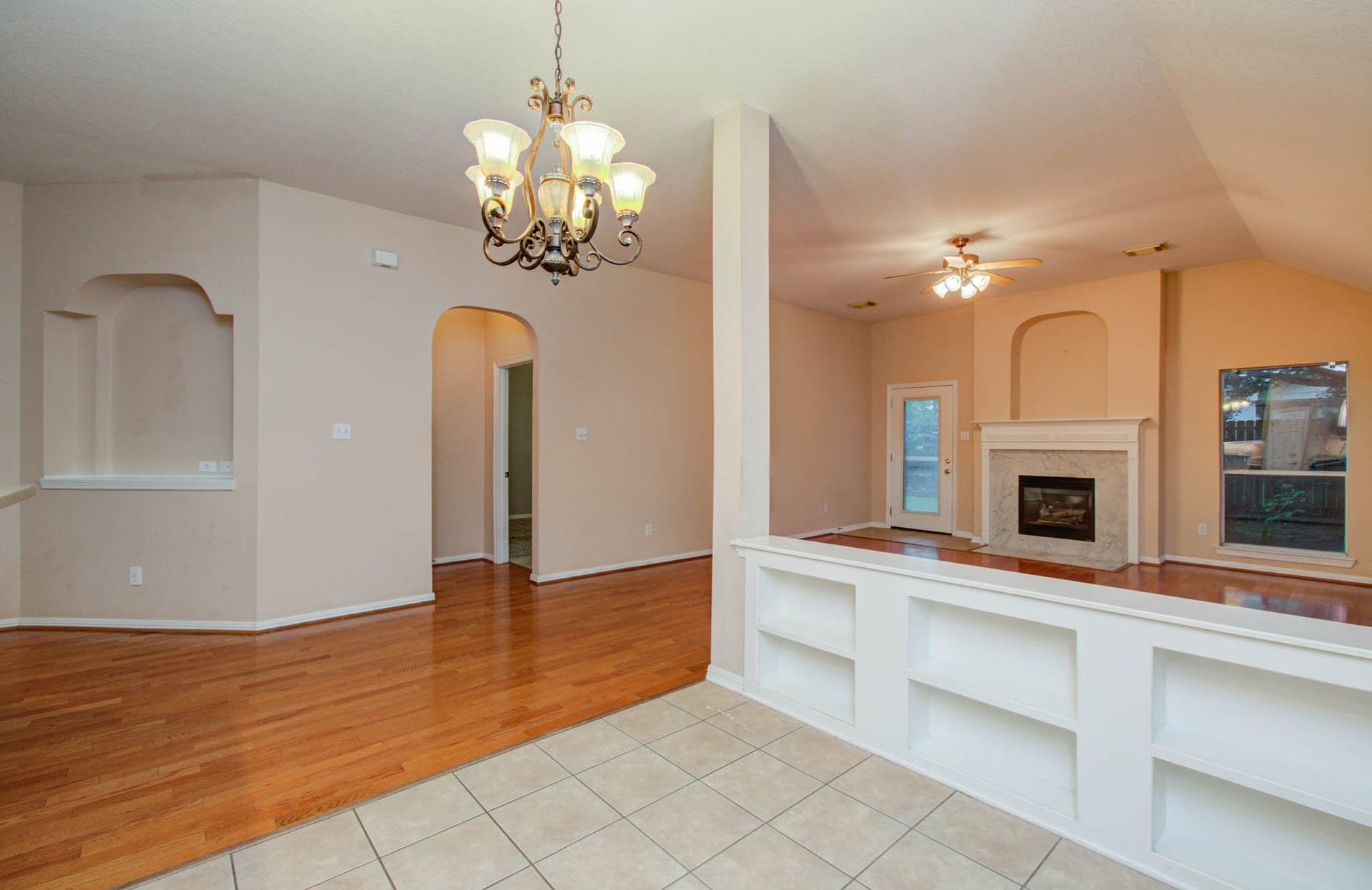 14403 Red Tailed Hawk Lane, Houston, TX 77044 Spacious open living area features elegant wood flooring, a cozy fireplace, and built-in shelving, complemented by a stylish chandelier and abundant natural light.